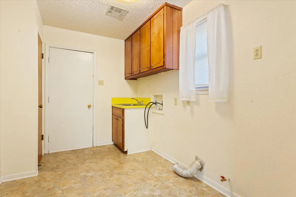 Laundry area with cabinet space, washer hookup, a textured ceiling, and gas dryer hookup
