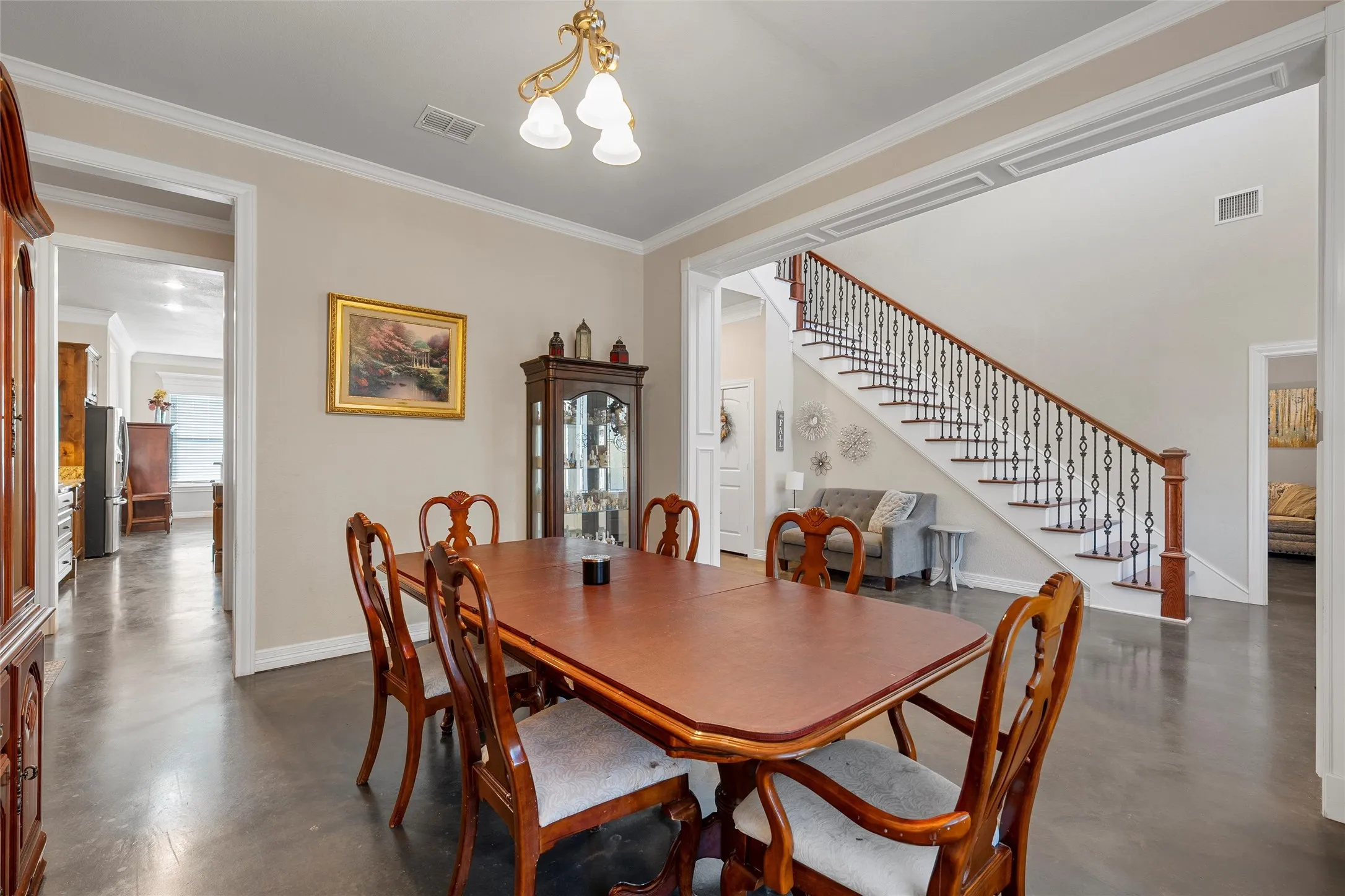 Dining room with finished concrete flooring, stairway, and crown molding
