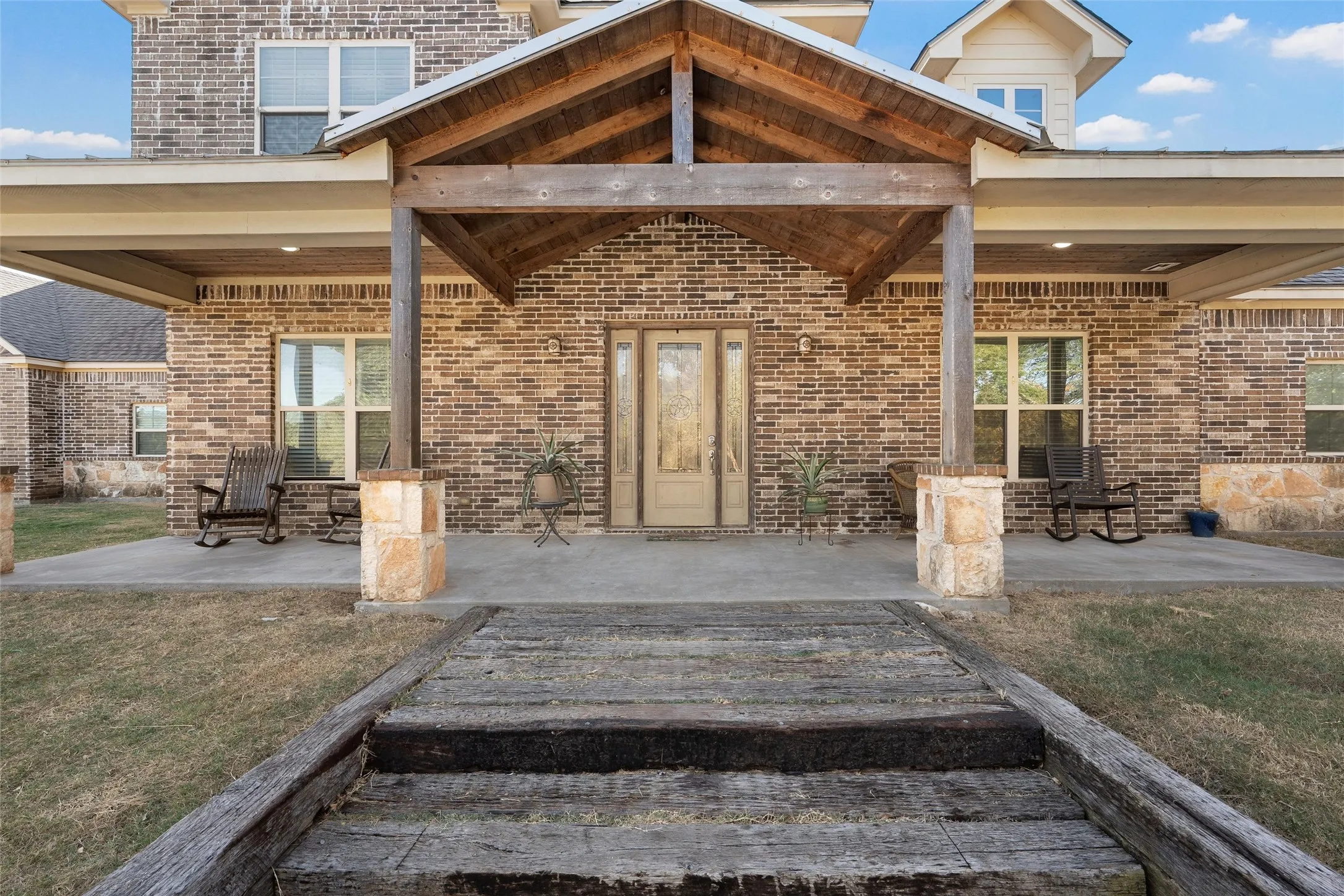 Doorway to property with a patio area, a yard, and brick siding