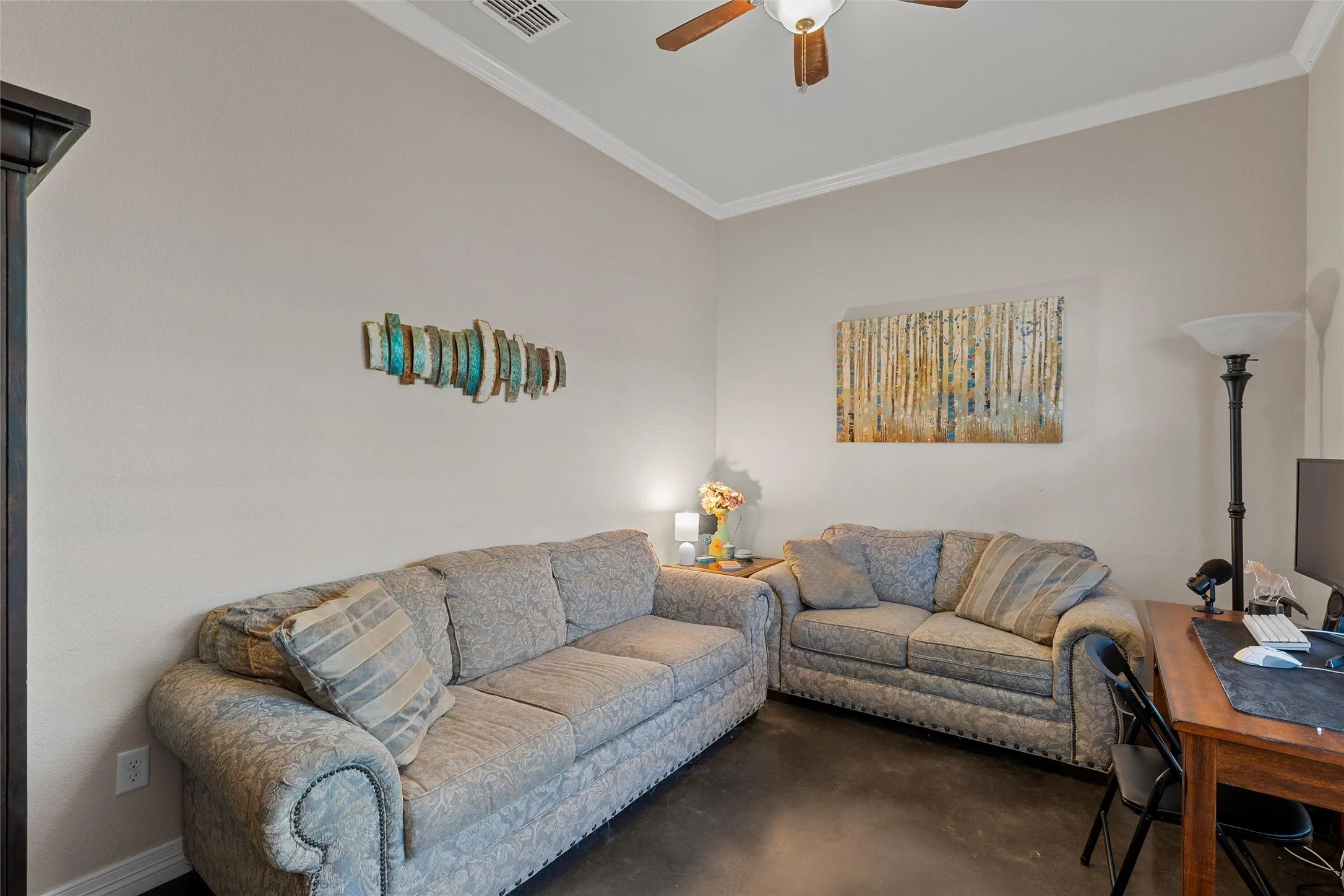 Living room featuring ornamental molding, concrete floors, a ceiling fan, and a desk