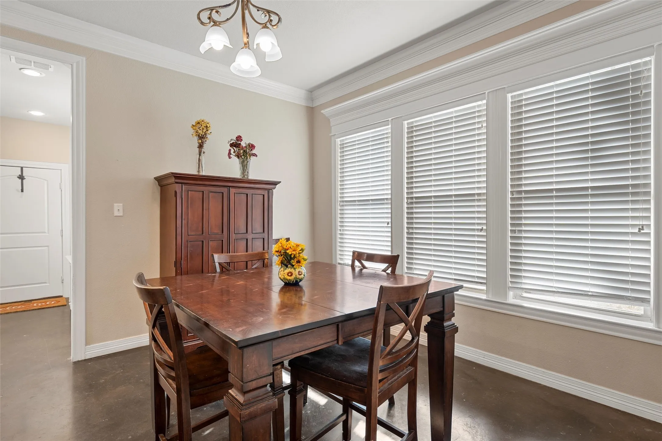 Dining area with concrete flooring, ornamental molding, and a chandelier