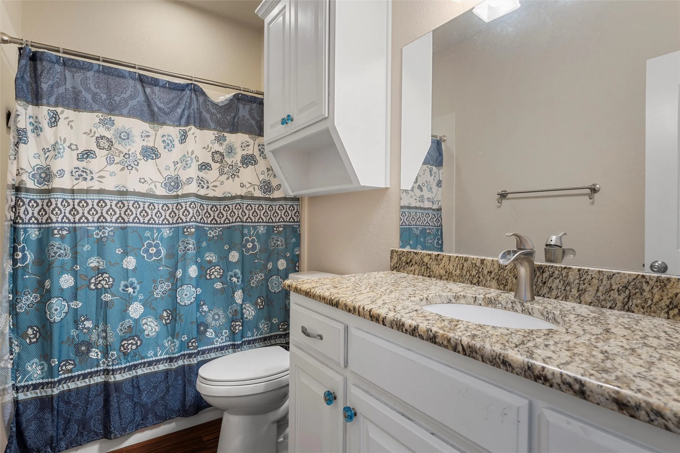 Full bathroom featuring vanity, shower / bath combo with shower curtain, and dark wood-style flooring