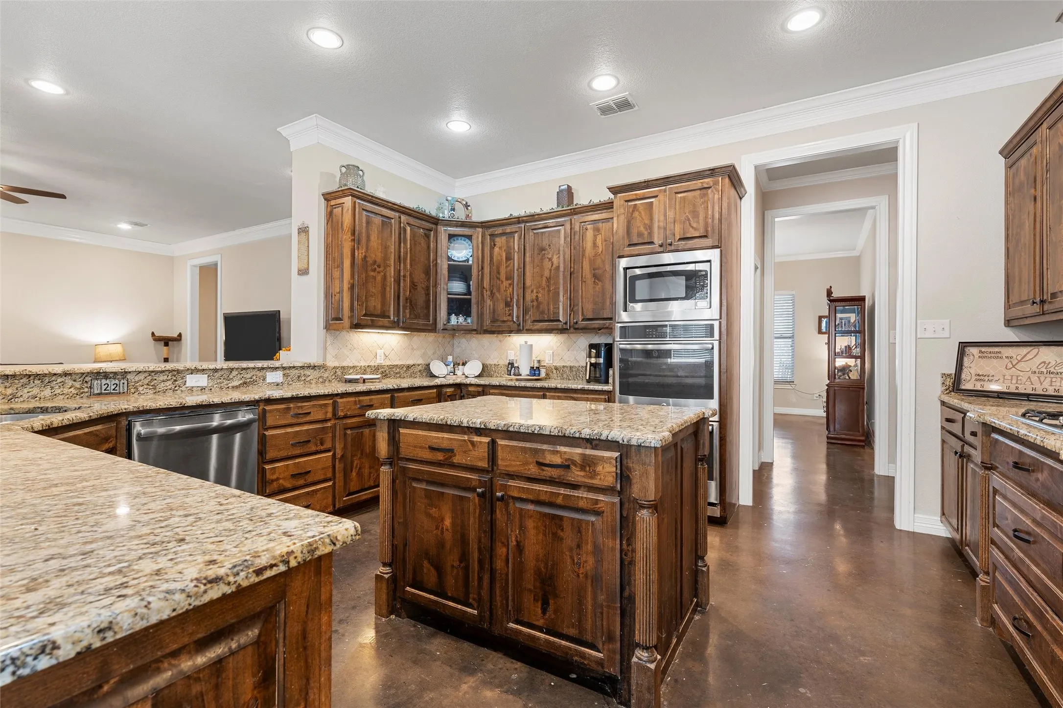 Kitchen featuring ornamental molding, backsplash, light stone countertops, concrete flooring, and a kitchen island