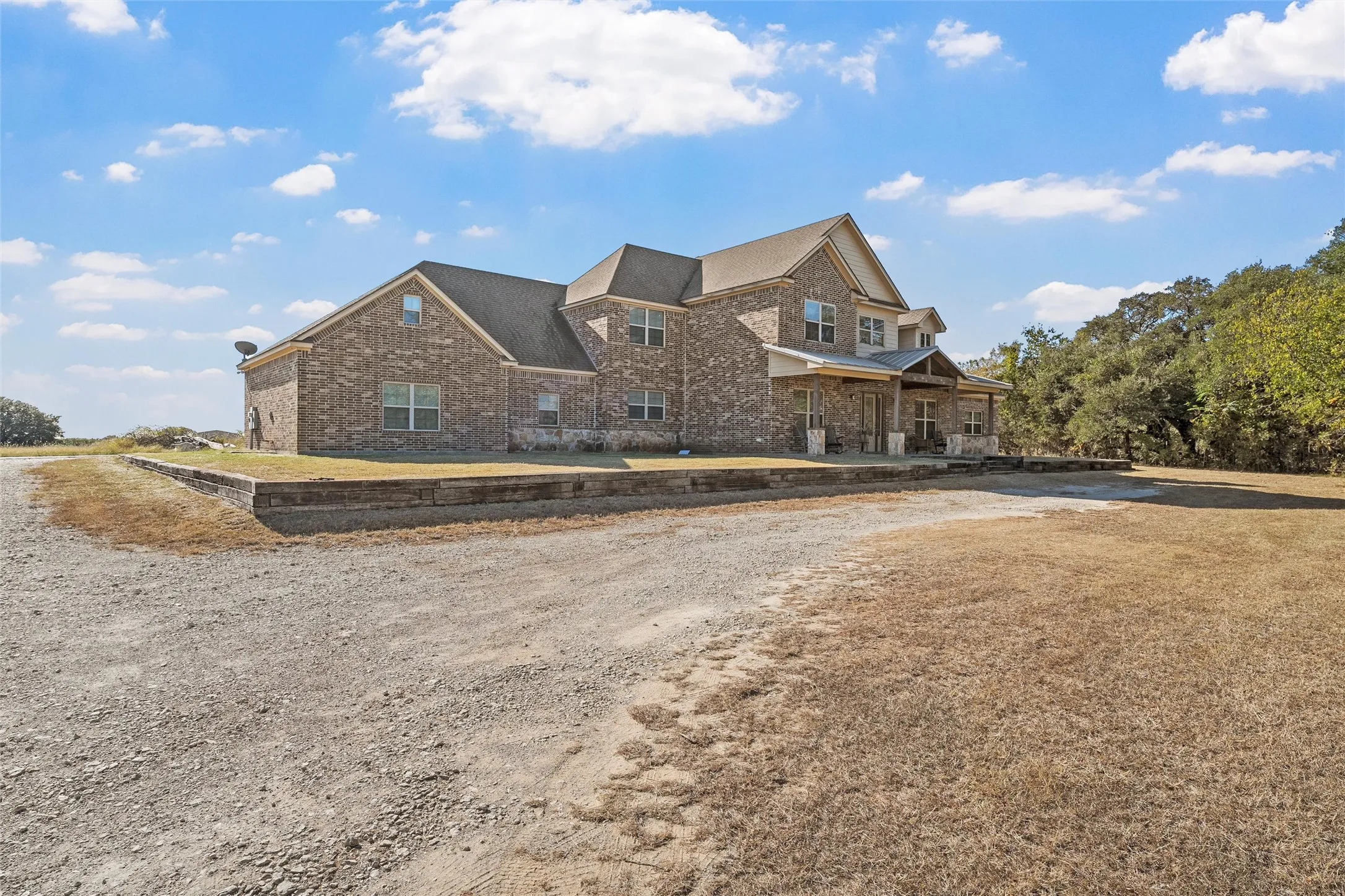 View of front of property with brick siding, covered porch, and a front yard