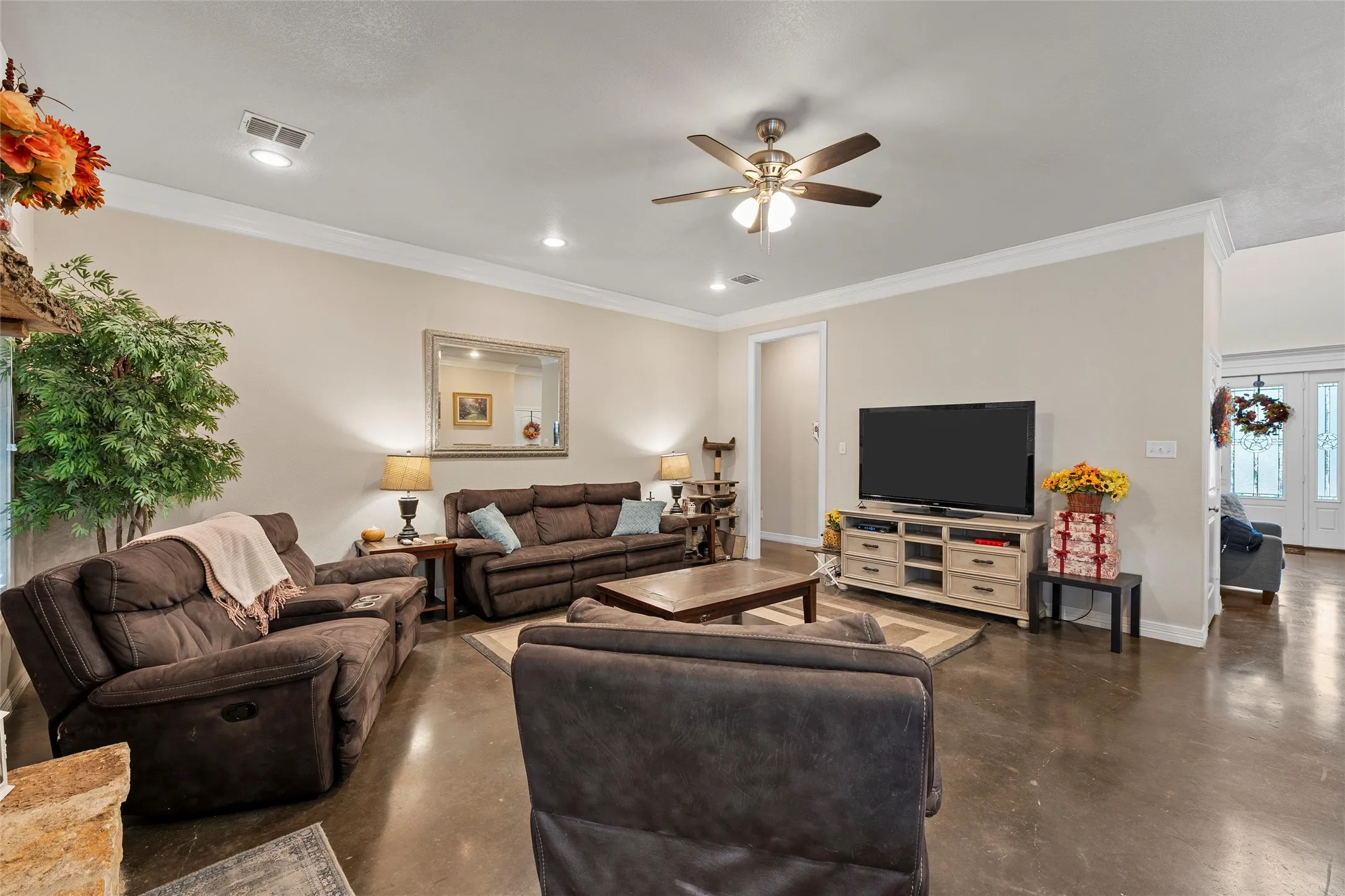 Living room featuring finished concrete floors, crown molding, a ceiling fan, and recessed lighting
