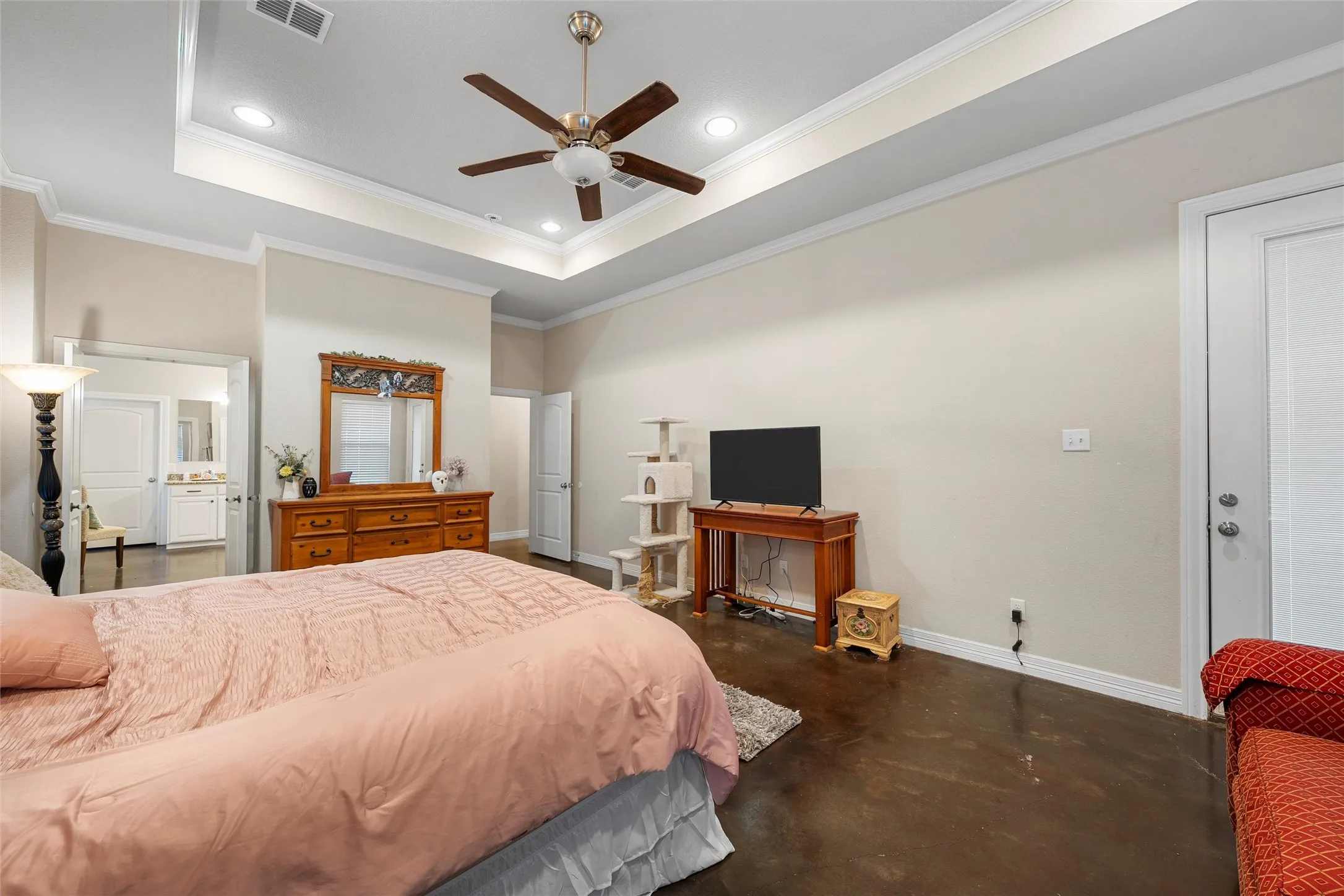 Primary Bedroom with a raised ceiling, concrete flooring, recessed lighting, ornamental molding, and a ceiling fan