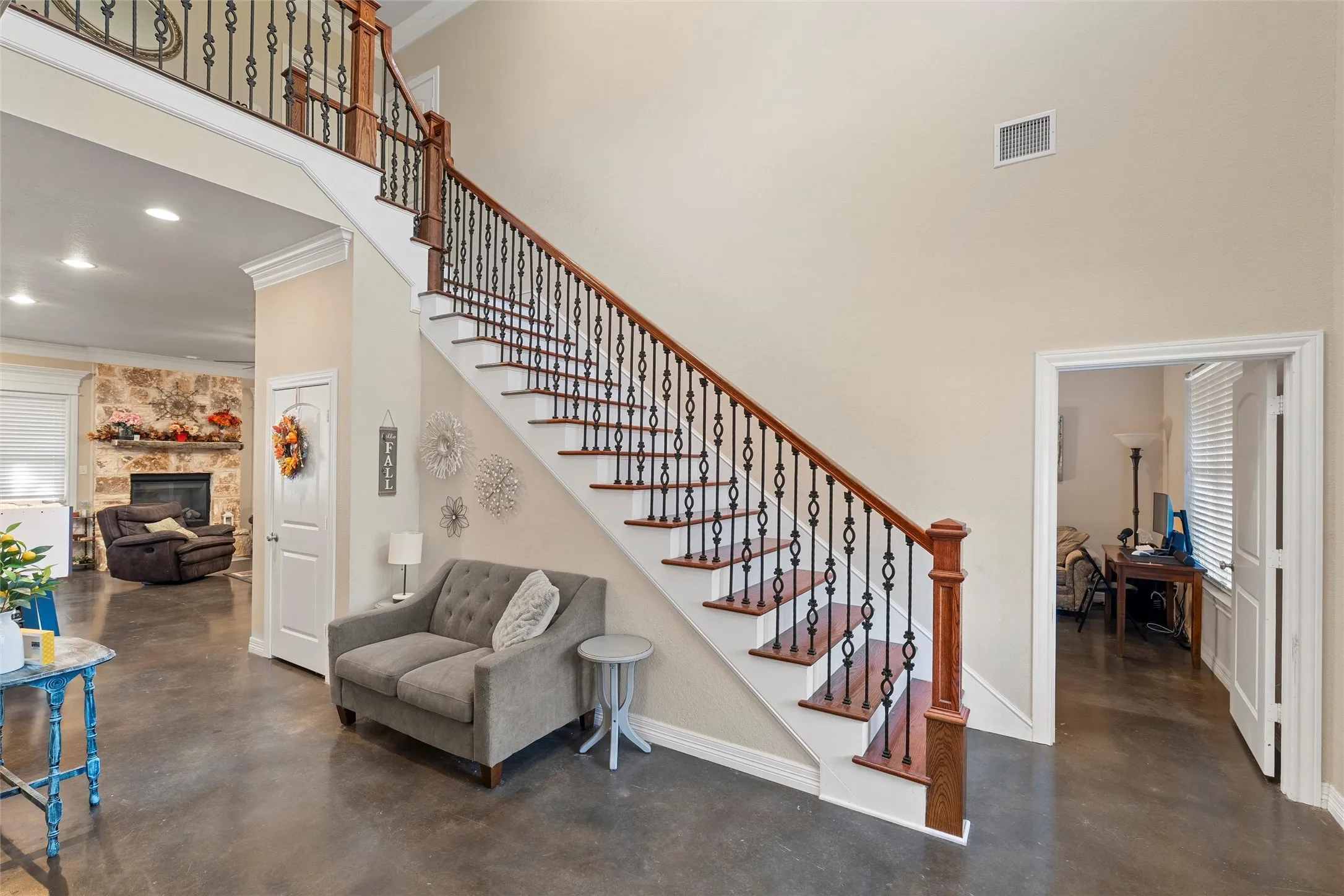 Stairway featuring a high ceiling, finished concrete flooring, a fireplace, ornamental molding, and recessed lighting