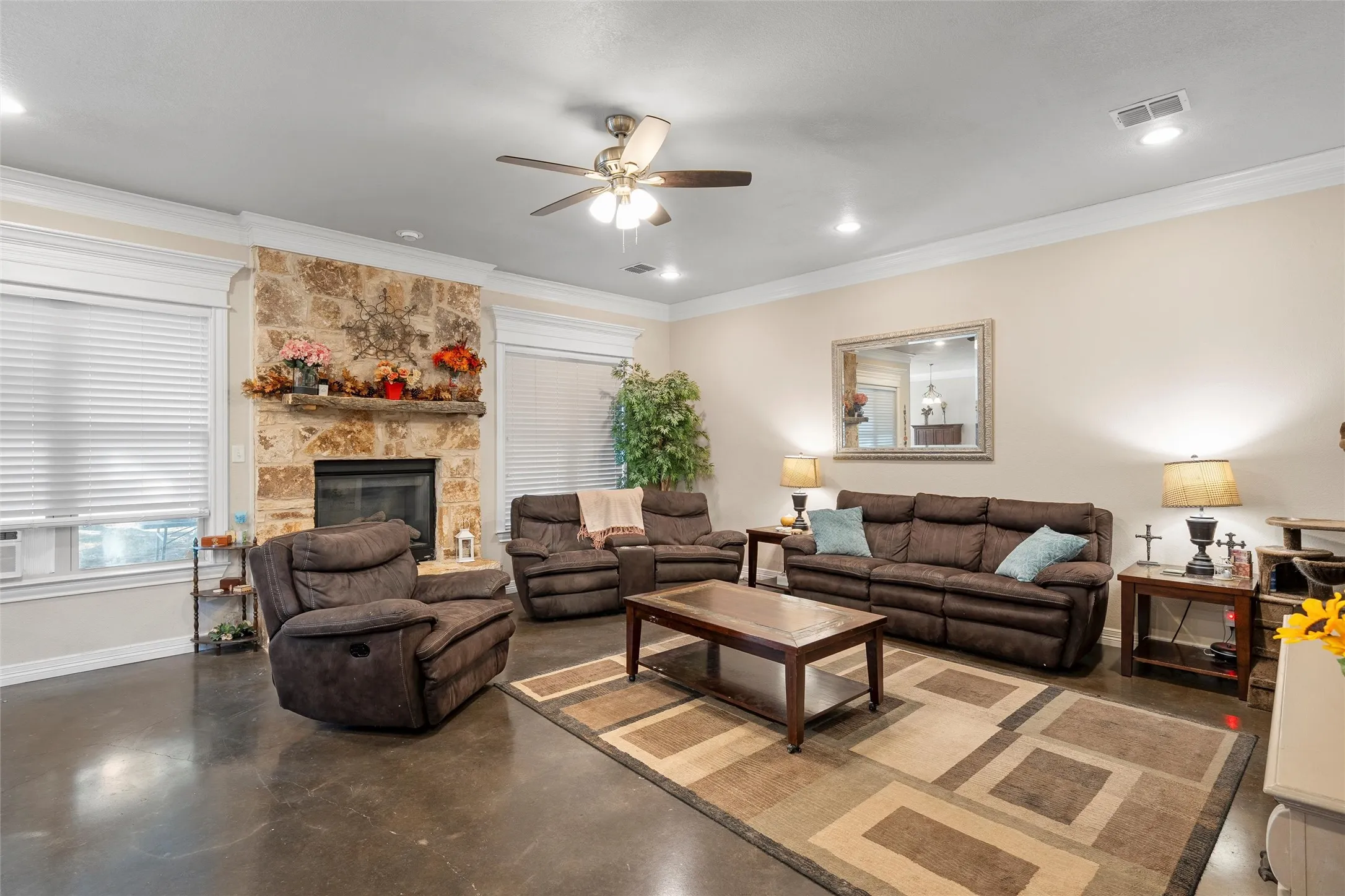 Living area featuring finished concrete flooring, ornamental molding, a ceiling fan, a fireplace, and recessed lighting