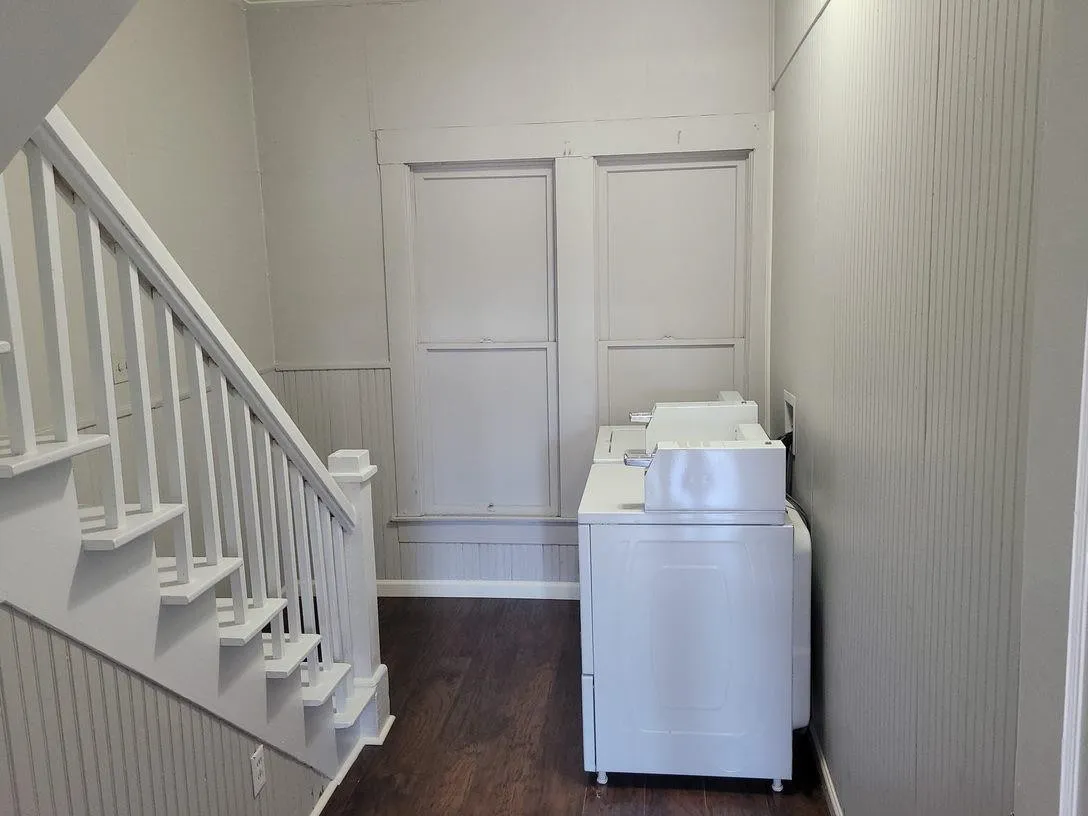 Washroom with dark wood-type flooring, washer / clothes dryer, and baseboards