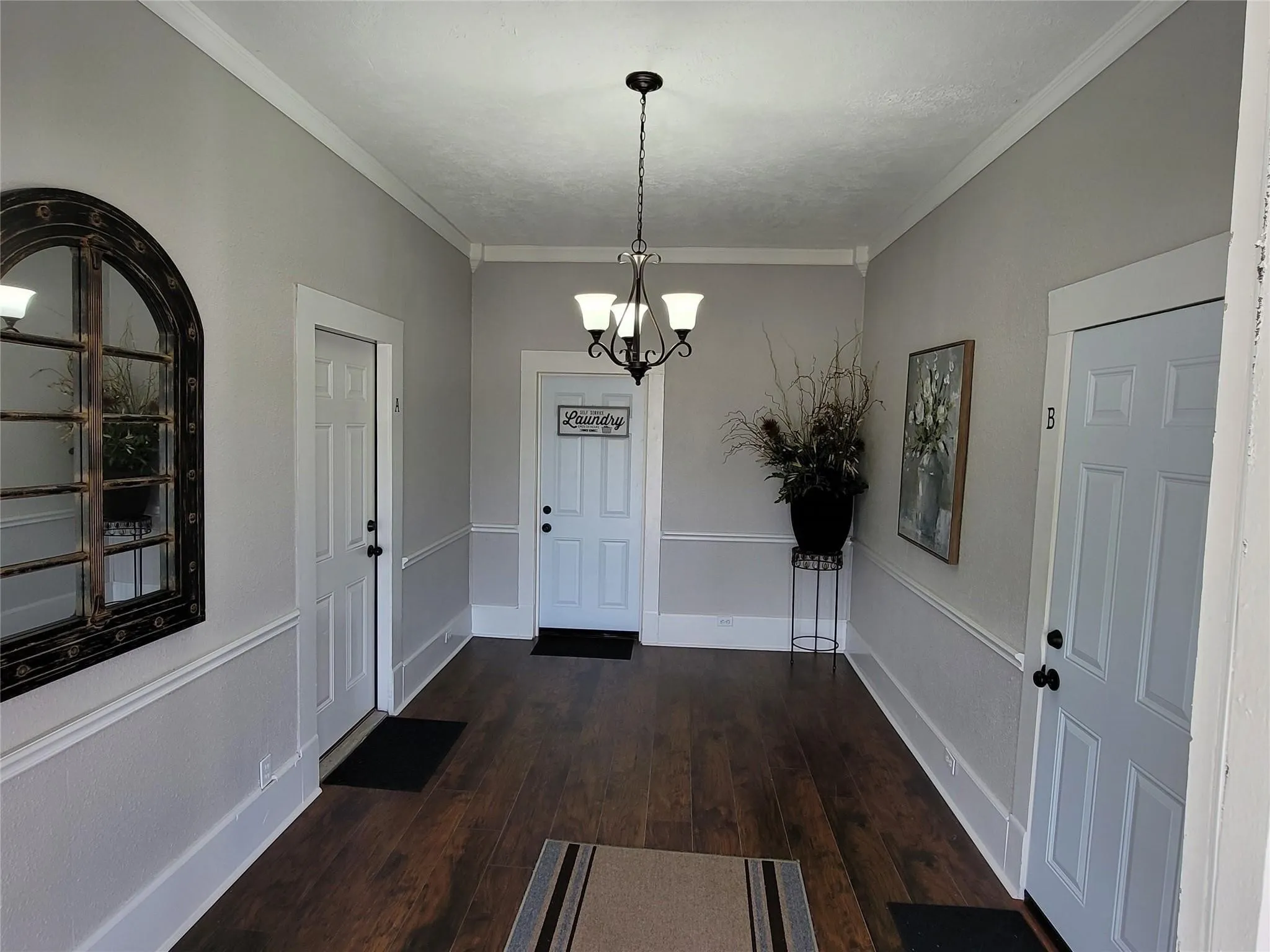 Entryway featuring crown molding, a notable chandelier, dark wood finished floors, and baseboards