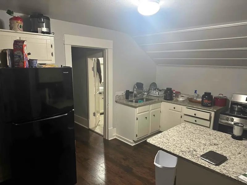 Kitchen with freestanding refrigerator, white cabinetry, stainless steel range oven, lofted ceiling, and light stone counters