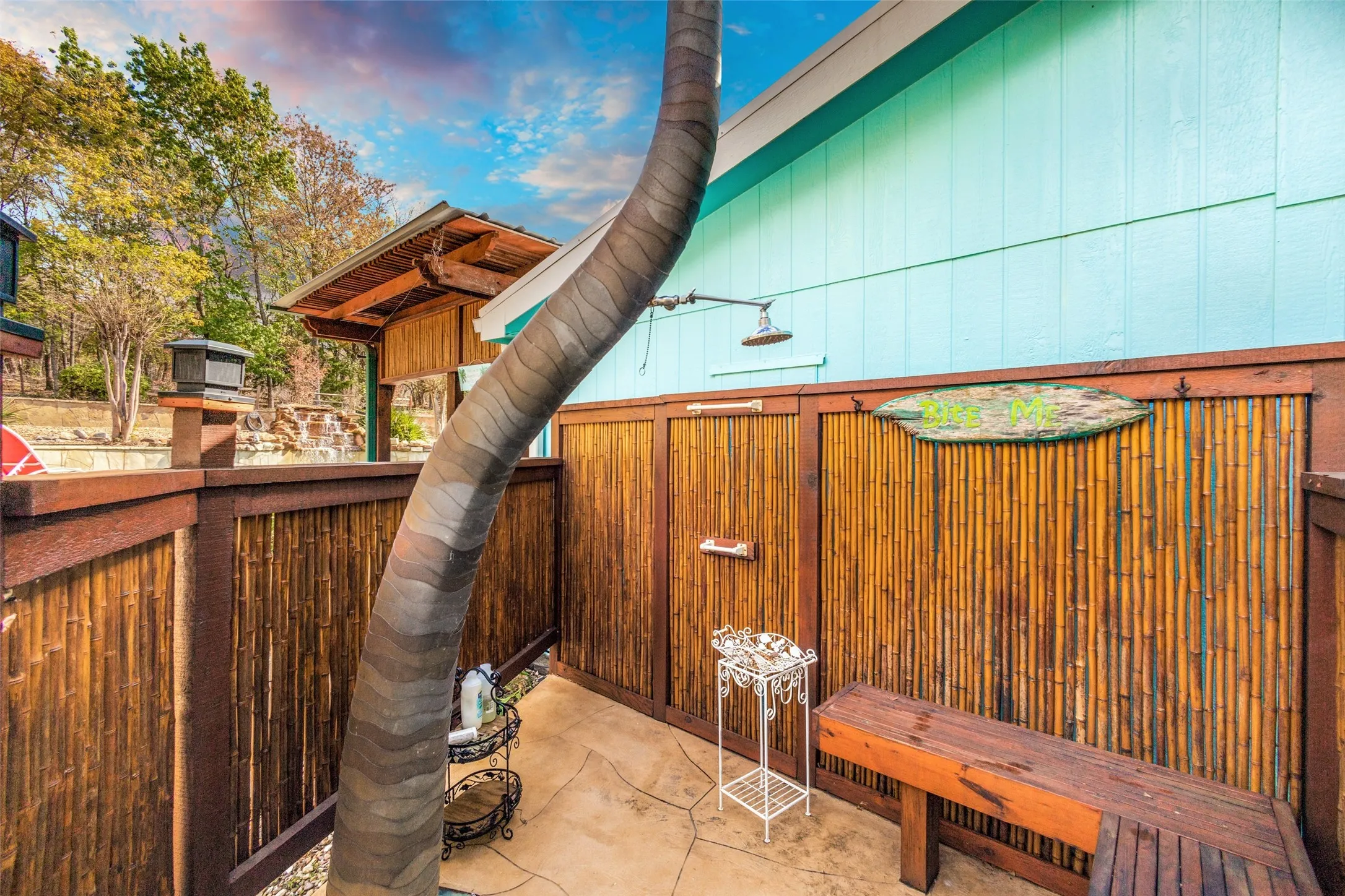 Interior View of the Bamboo Wrapped Outdoor Shower Featuring a Built-in Bench and Poolside Access. Metal Palm Tree.