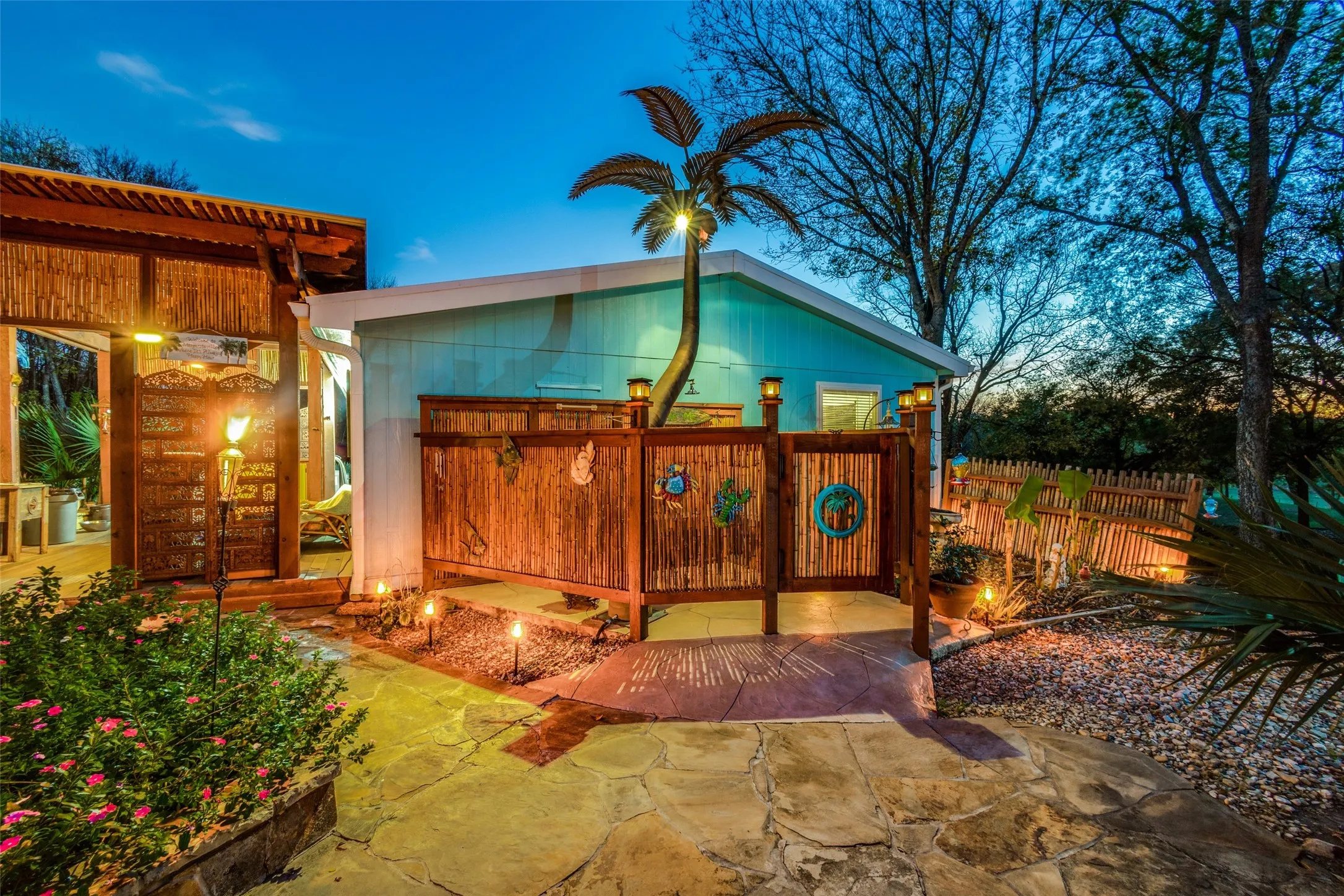Tropical Outdoor Shower with Private Door and Built-in Bench, and a Glowing, Metal Palm Tree Complete with Lights and a Playful Monkey at the Top. The Perfect Pool Shower For Rinsing Off After a Swim.