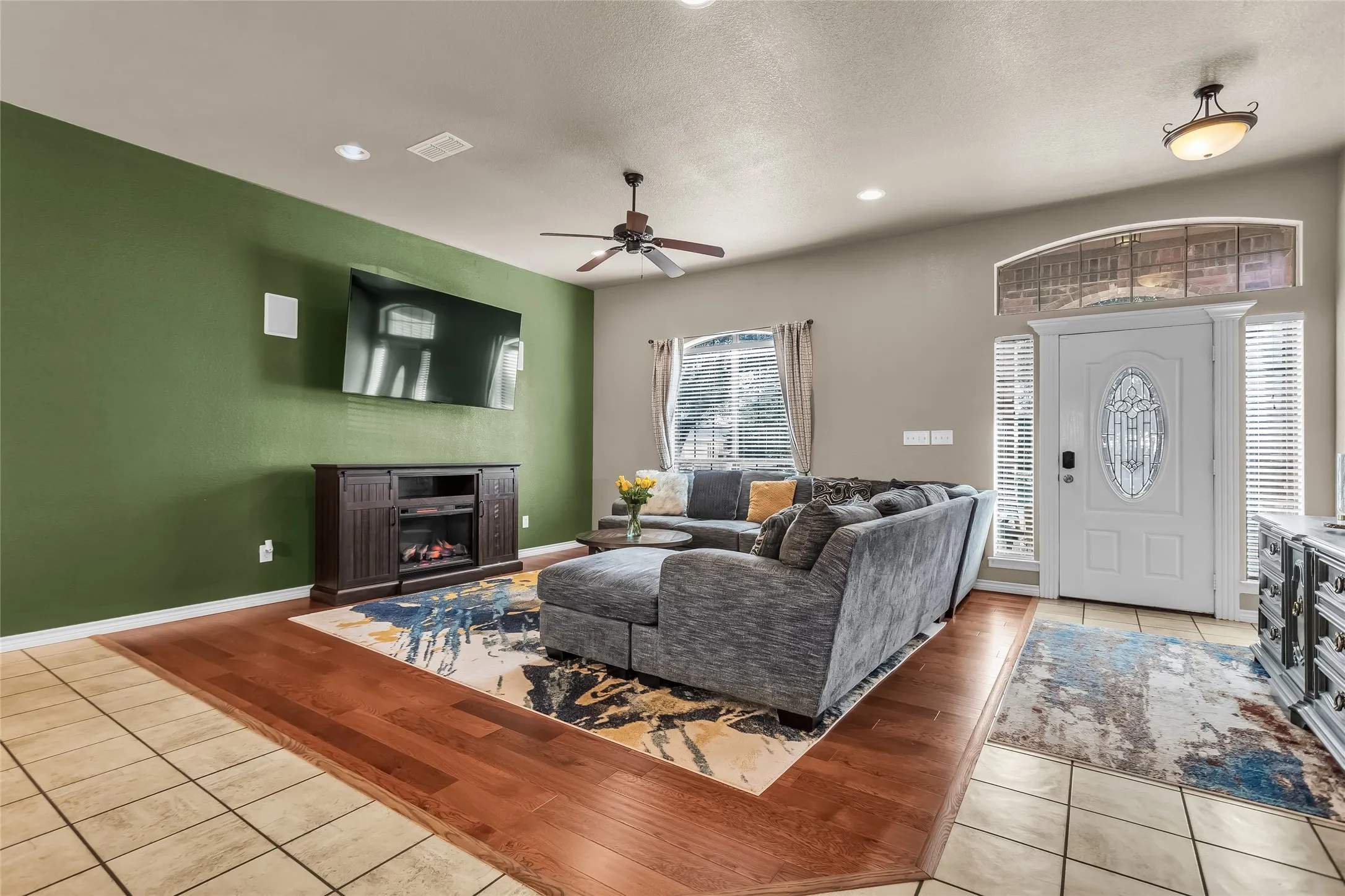 Living area with light wood finished floors, a warm lit fireplace, recessed lighting, a textured ceiling, and ceiling fan