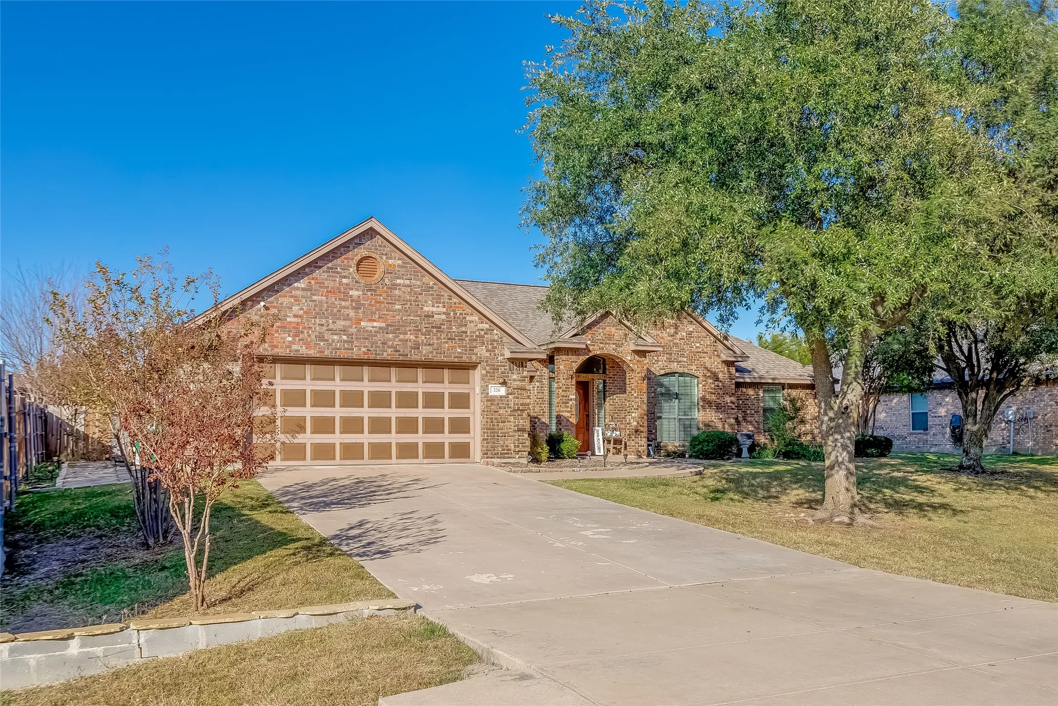 View of front facade featuring brick siding, concrete driveway, a front lawn, a garage, and a shingled roof