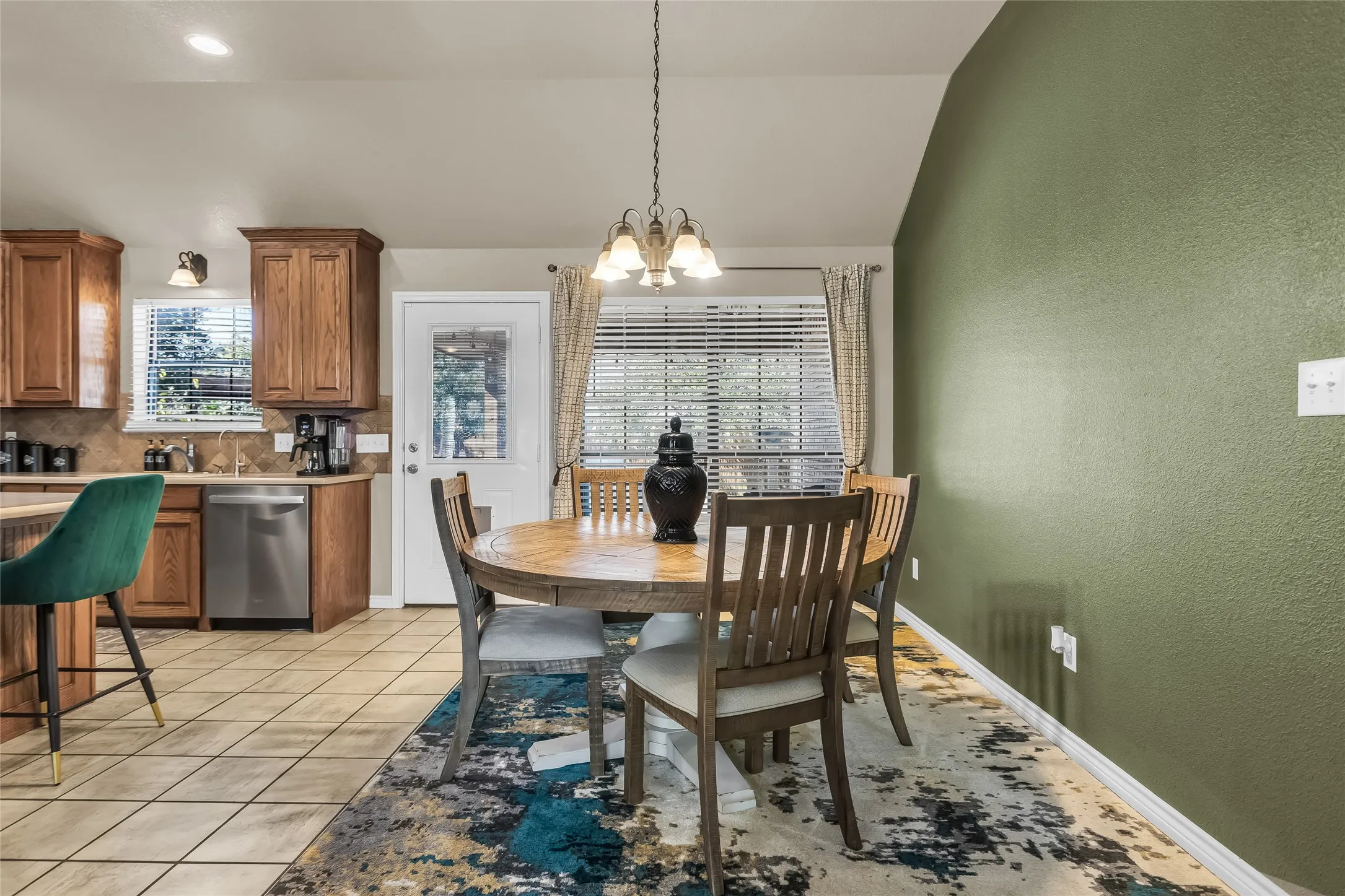 Dining space with a chandelier, light tile patterned floors, a textured wall, and lofted ceiling