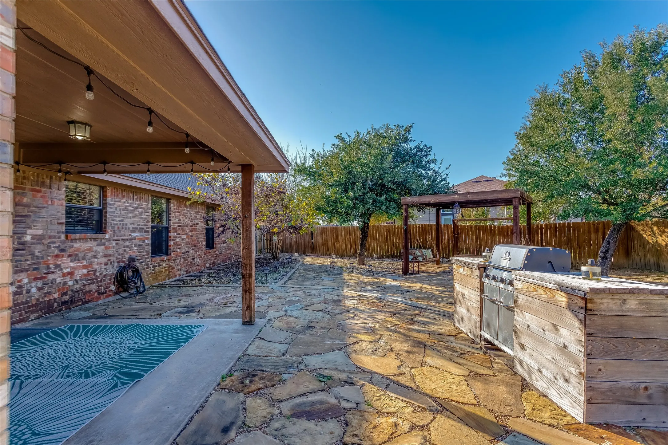Fenced backyard featuring a patio area and an outdoor kitchen