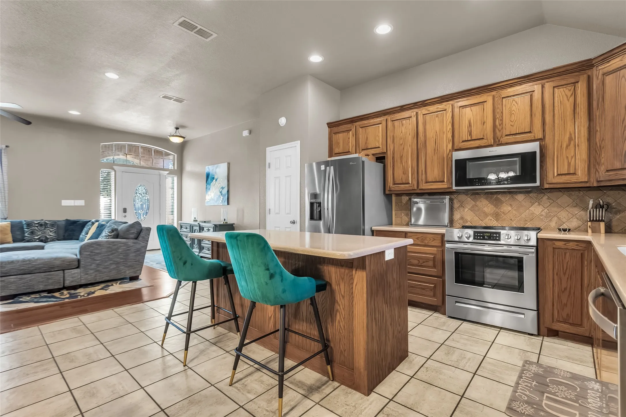 Kitchen featuring brown cabinetry, open floor plan, a center island, a breakfast bar area, and stainless steel appliances