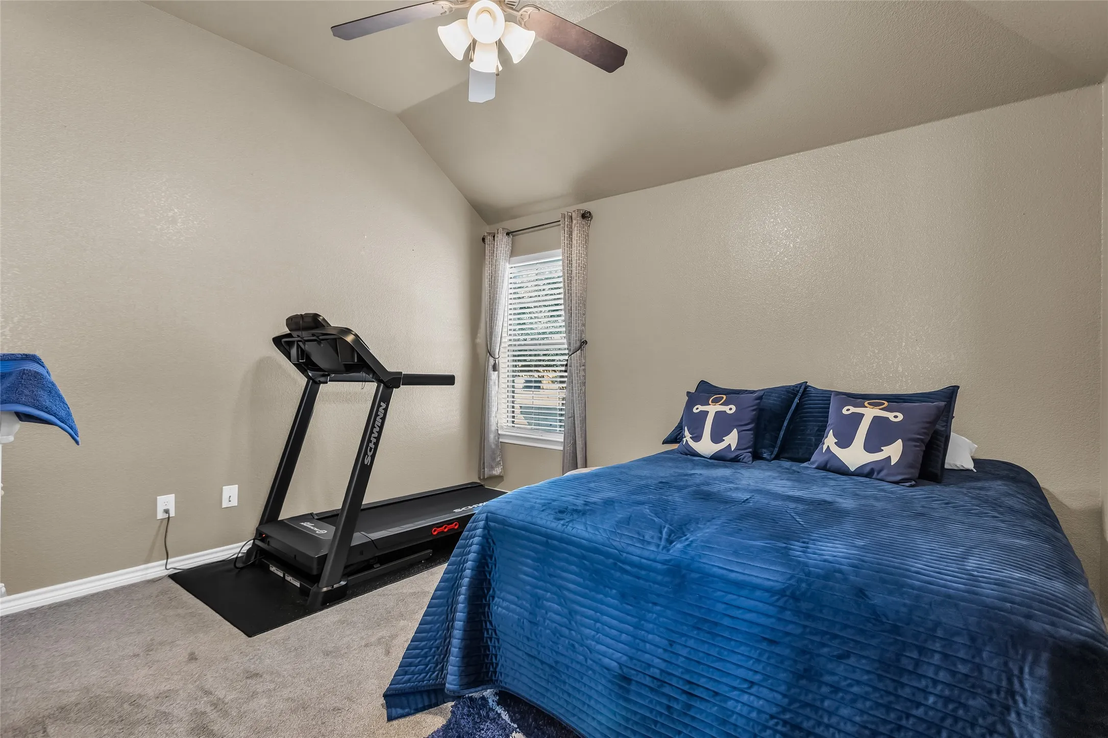 Bedroom featuring vaulted ceiling, a textured wall, carpet flooring, and a ceiling fan