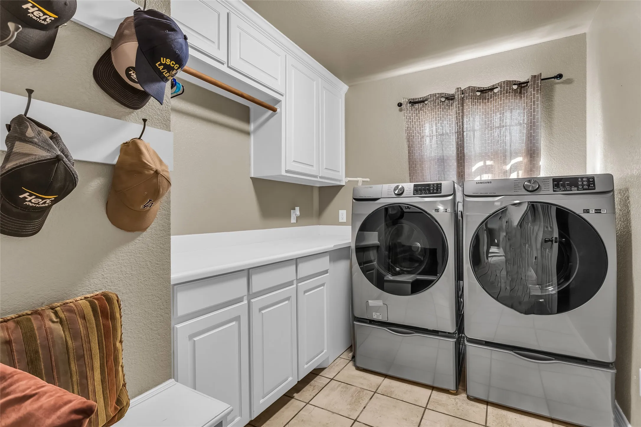Laundry room with light tile patterned floors, a textured wall, washer and clothes dryer, a textured ceiling, and cabinet space