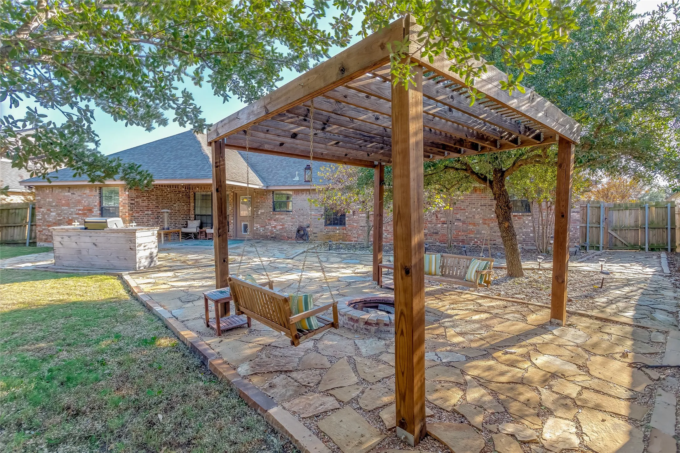 Fenced backyard with a patio area, a pergola, and an outdoor kitchen