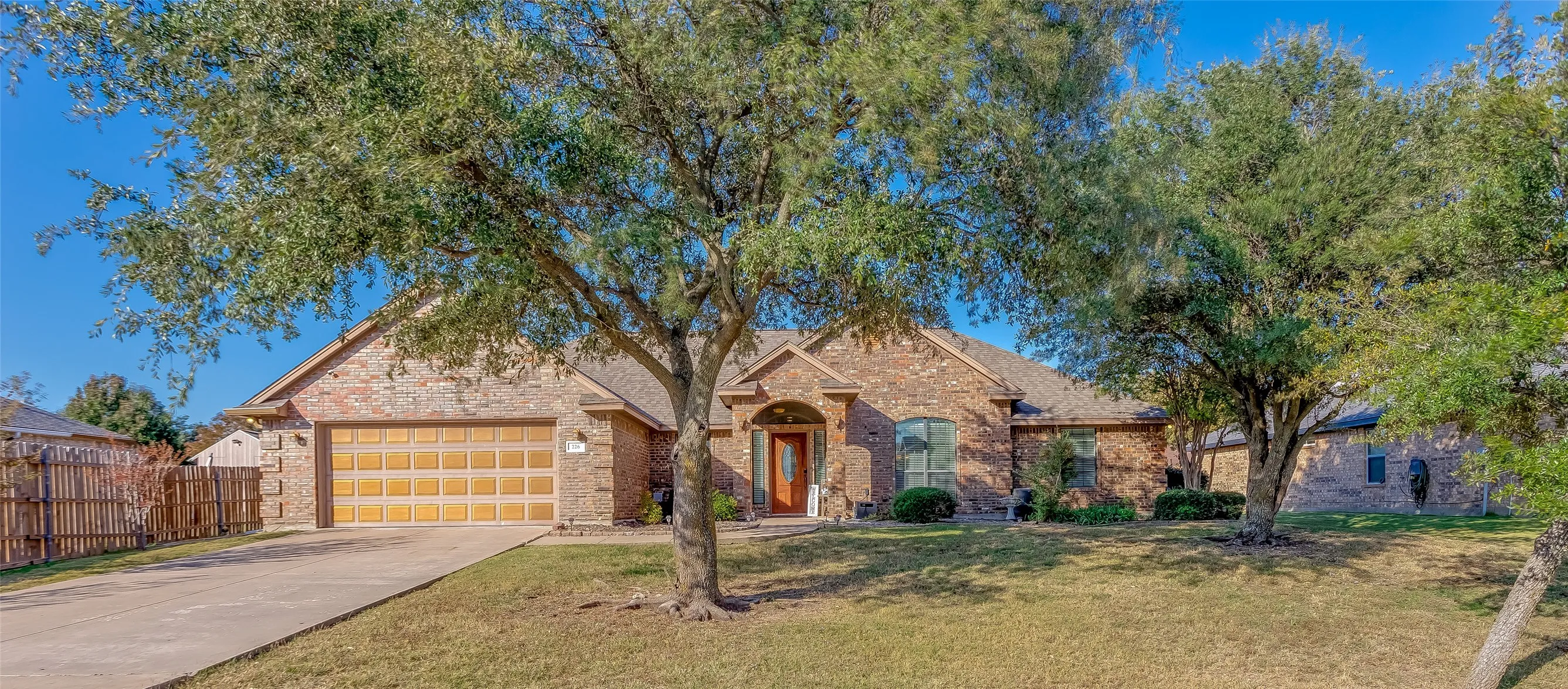 Traditional home featuring driveway, brick siding, a garage, and a shingled roof