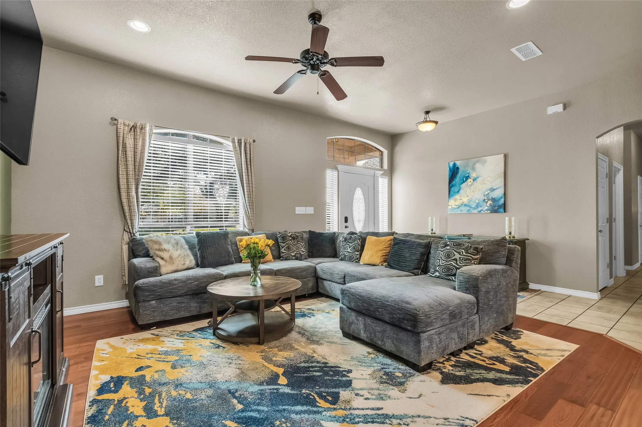 Living room featuring arched walkways, recessed lighting, lofted ceiling, a chandelier, and ceiling fan
