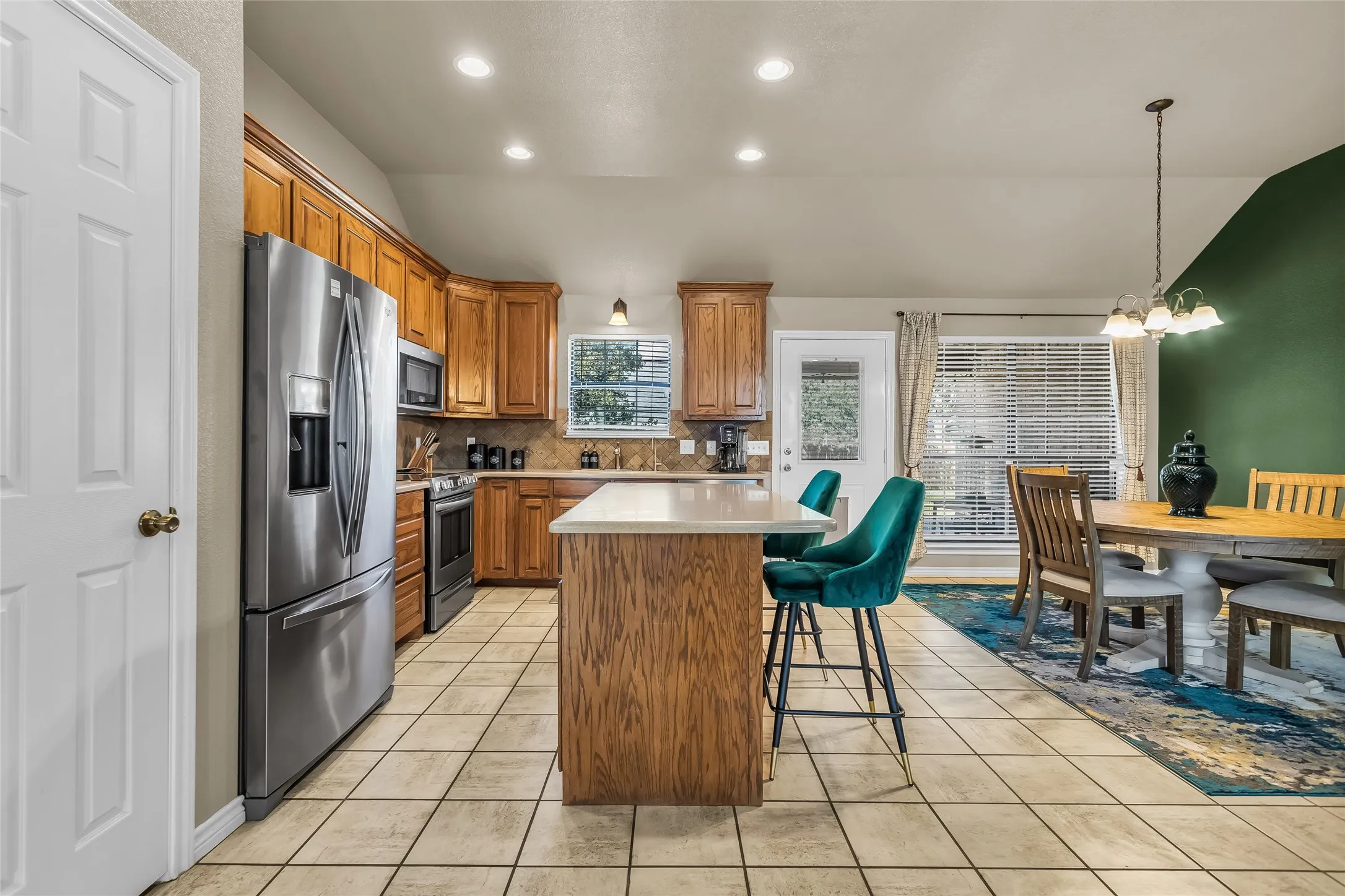 Kitchen with brown cabinets, tasteful backsplash, a kitchen breakfast bar, stainless steel appliances, and a kitchen island