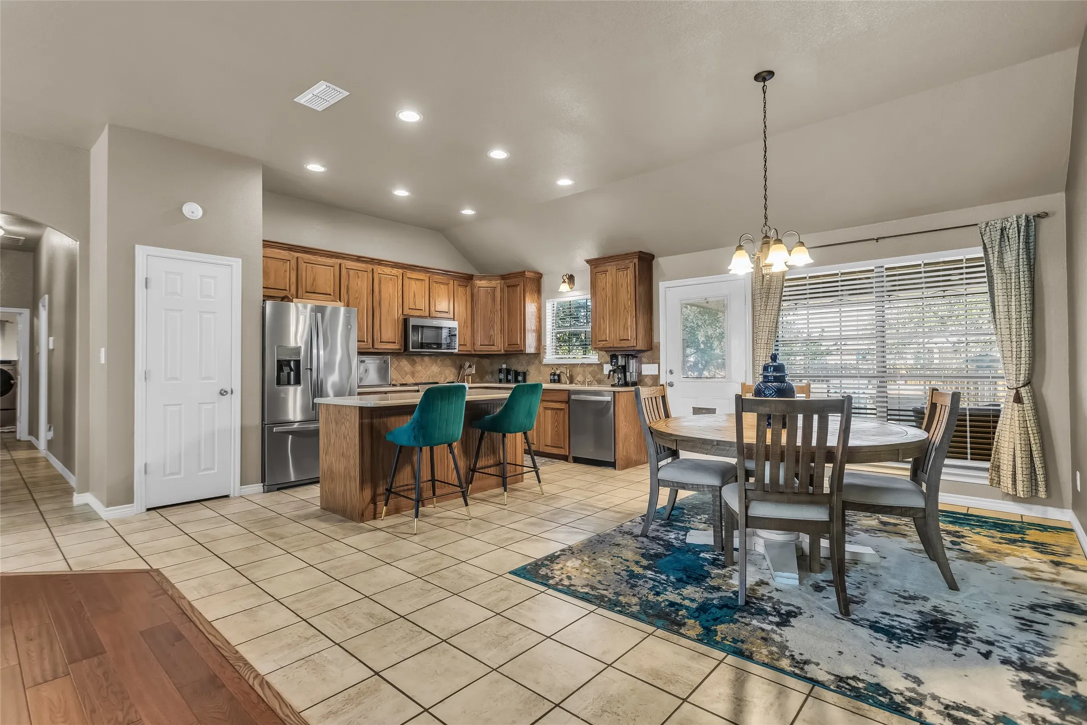 Dining space featuring a chandelier, light tile patterned floors, vaulted ceiling, recessed lighting, and arched walkways
