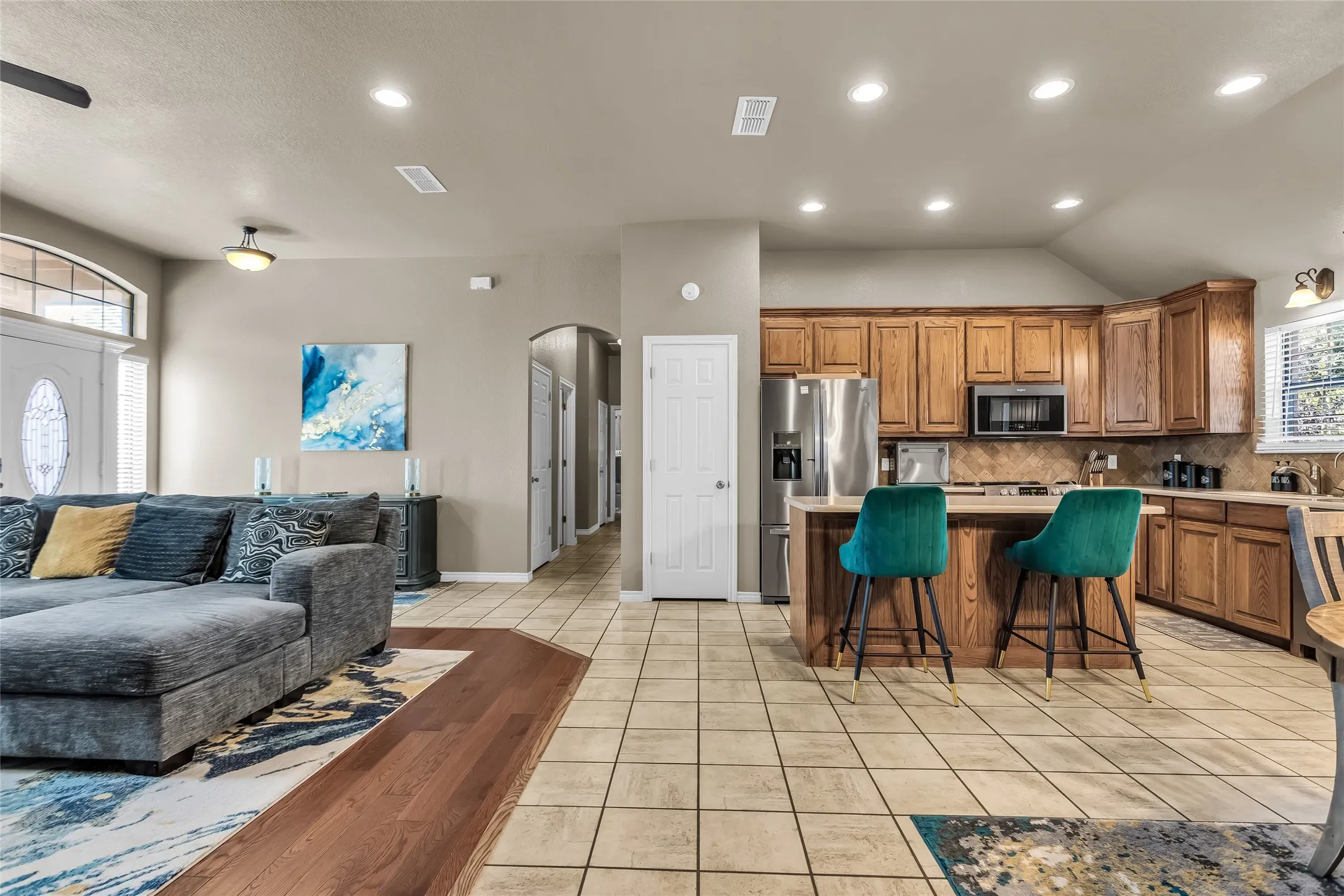 Kitchen with brown cabinets, open floor plan, light tile patterned floors, a kitchen island, and a breakfast bar area