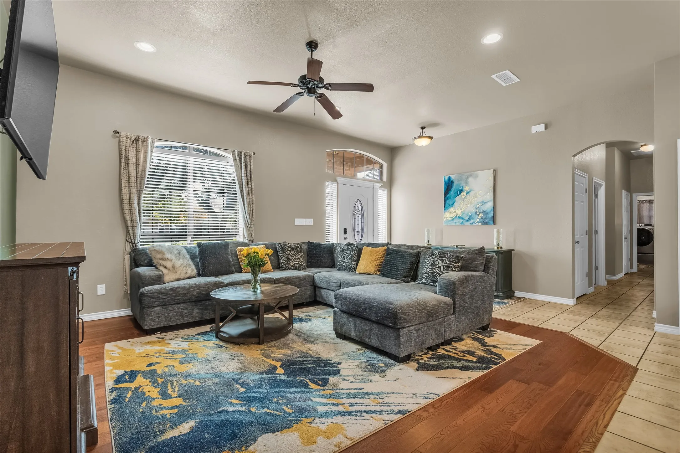 Living room featuring arched walkways, a ceiling fan, light wood-style flooring, recessed lighting, and washer / clothes dryer