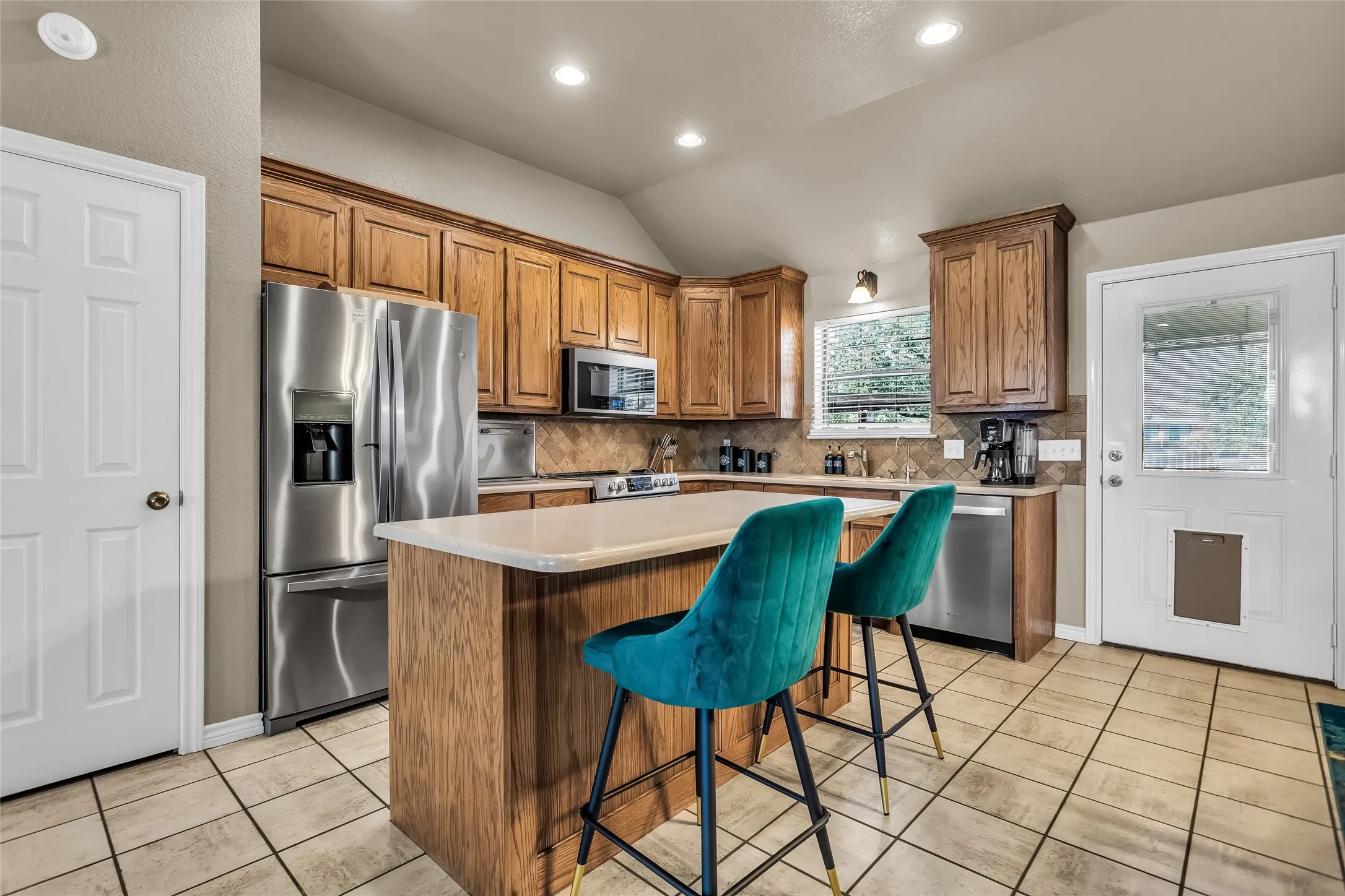 Kitchen featuring a kitchen island, a kitchen bar, brown cabinets, vaulted ceiling, and decorative backsplash