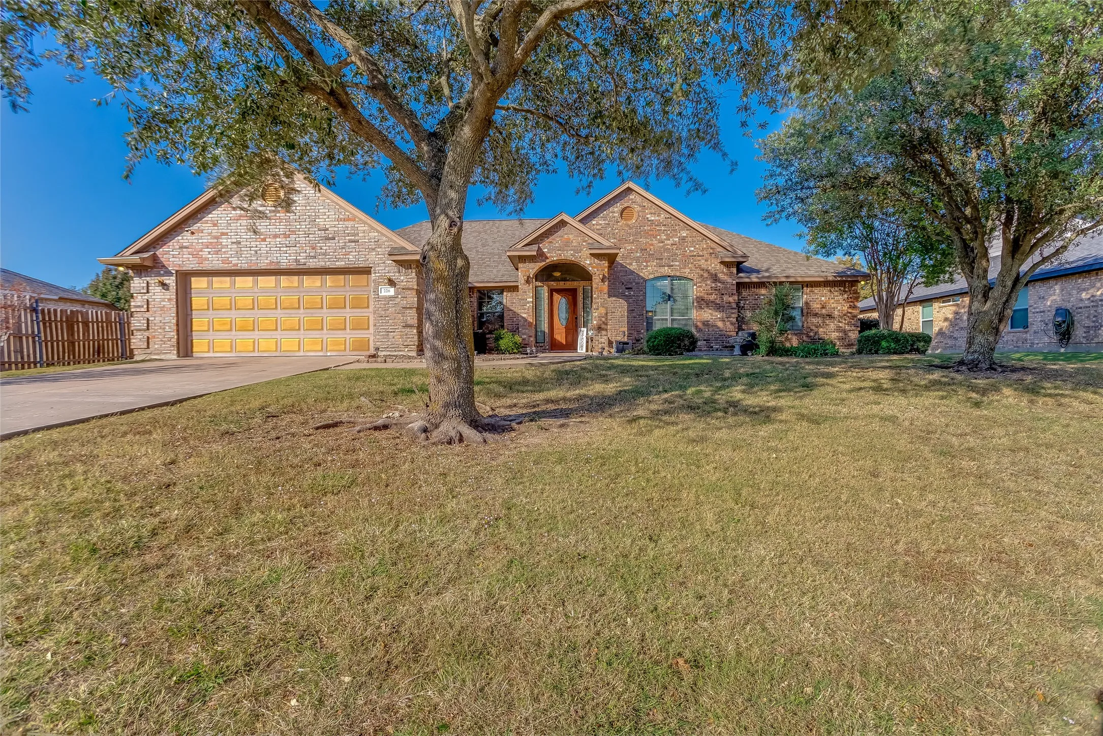 Ranch-style home with driveway, brick siding, and an attached garage