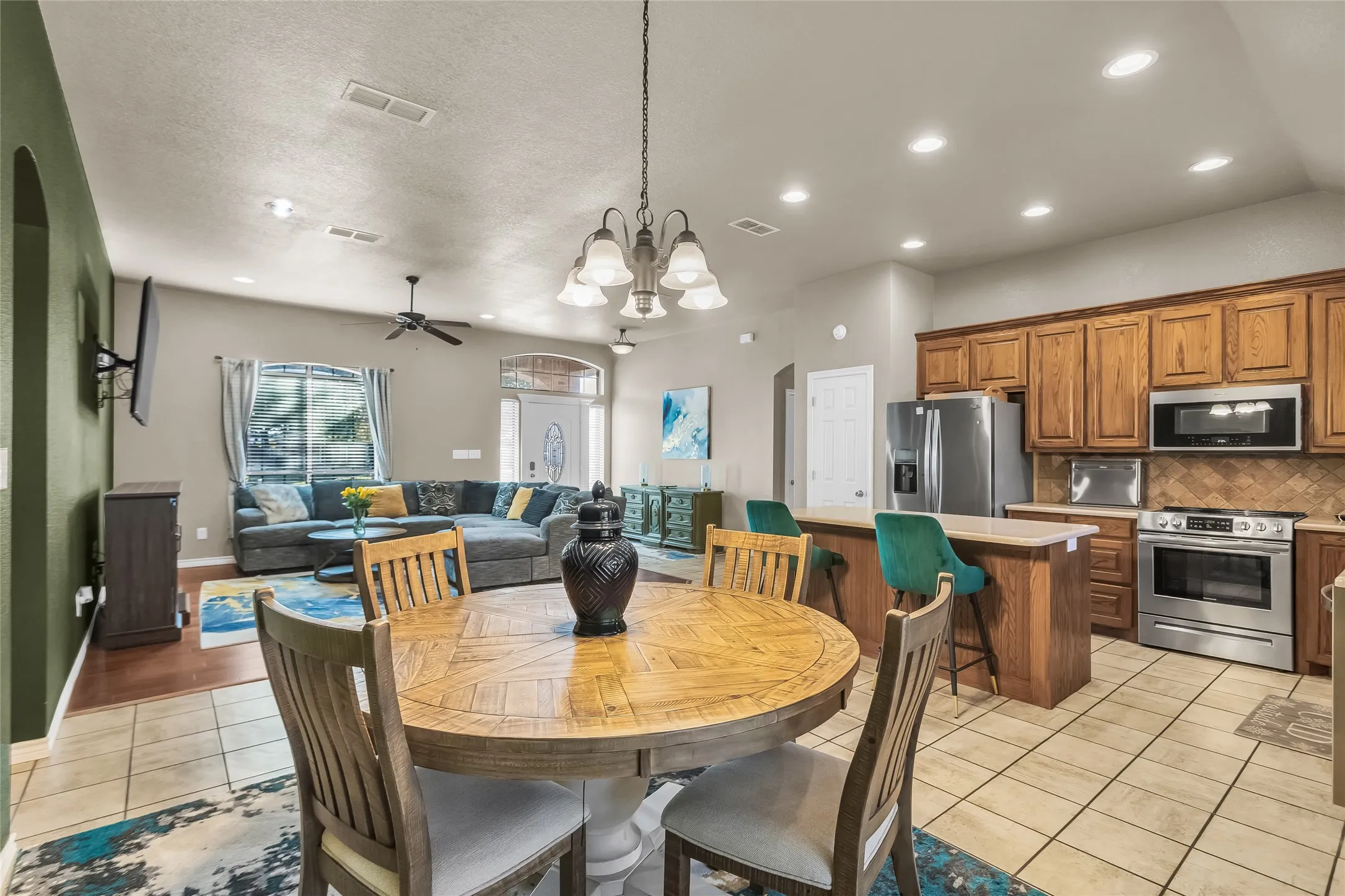 Dining area featuring a chandelier, light tile patterned flooring, recessed lighting, ceiling fan, and arched walkways