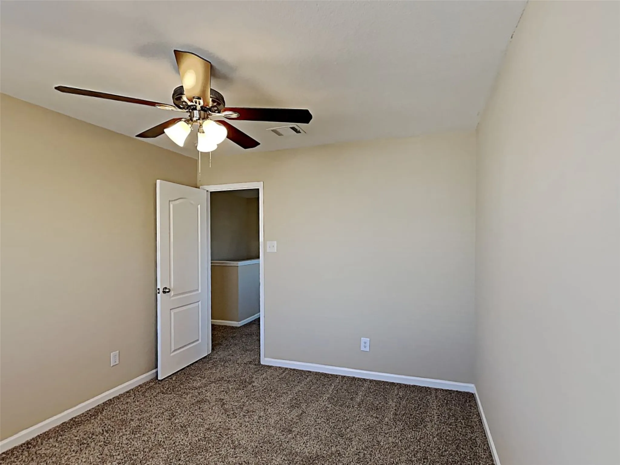 Empty room featuring dark carpet and a ceiling fan