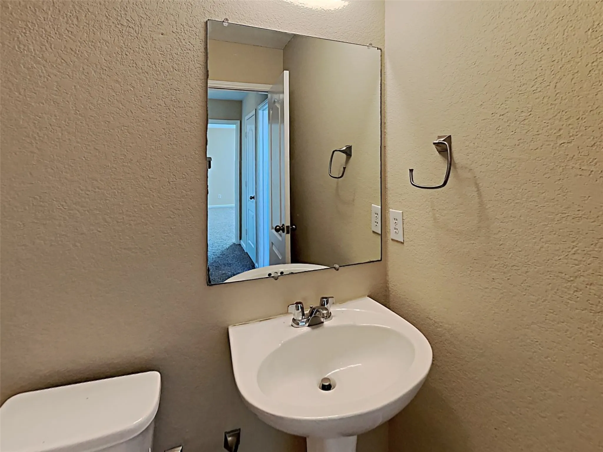 Bathroom featuring a textured wall and a sink