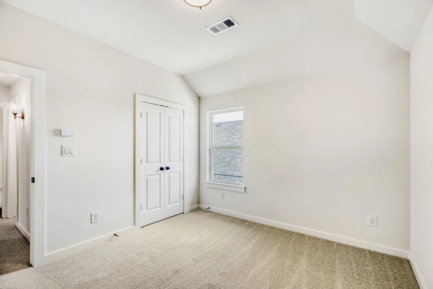 Carpeted room featuring white walls, a vaulted ceiling, a double-door closet, and a window with white trim