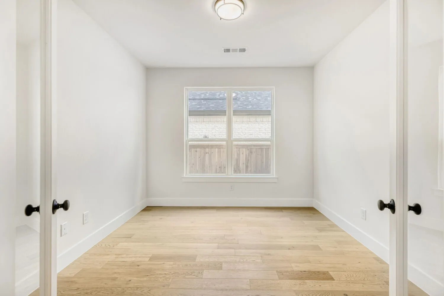 Bright room featuring wood-finish flooring, white baseboards, and a white ceiling with a flush-mount light fixture