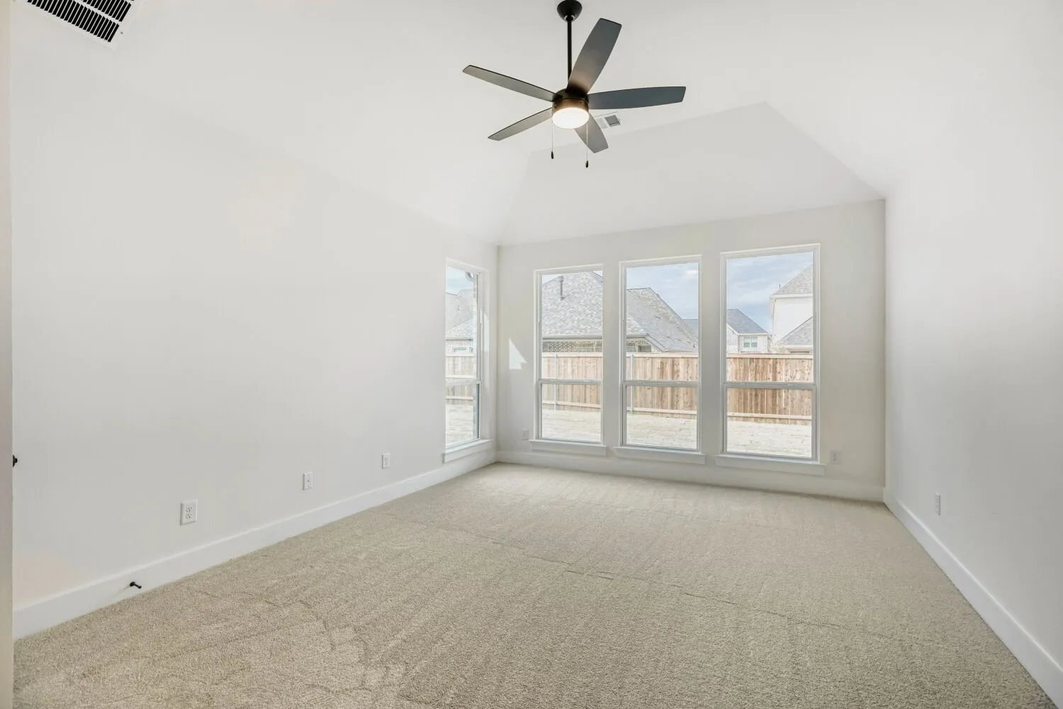 Spacious room featuring vaulted ceilings, a contemporary ceiling fan with integrated lighting, and plush carpet flooring