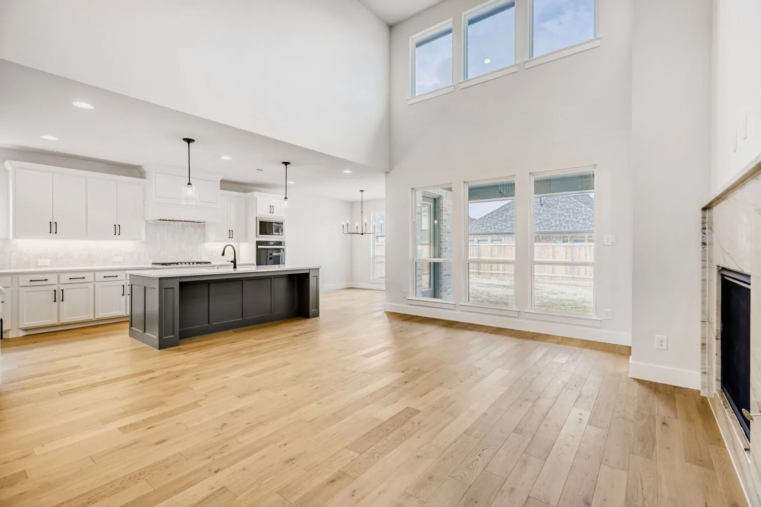 Vaulted ceiling living space with wood-finish flooring, a contemporary fireplace, and multiple windows
