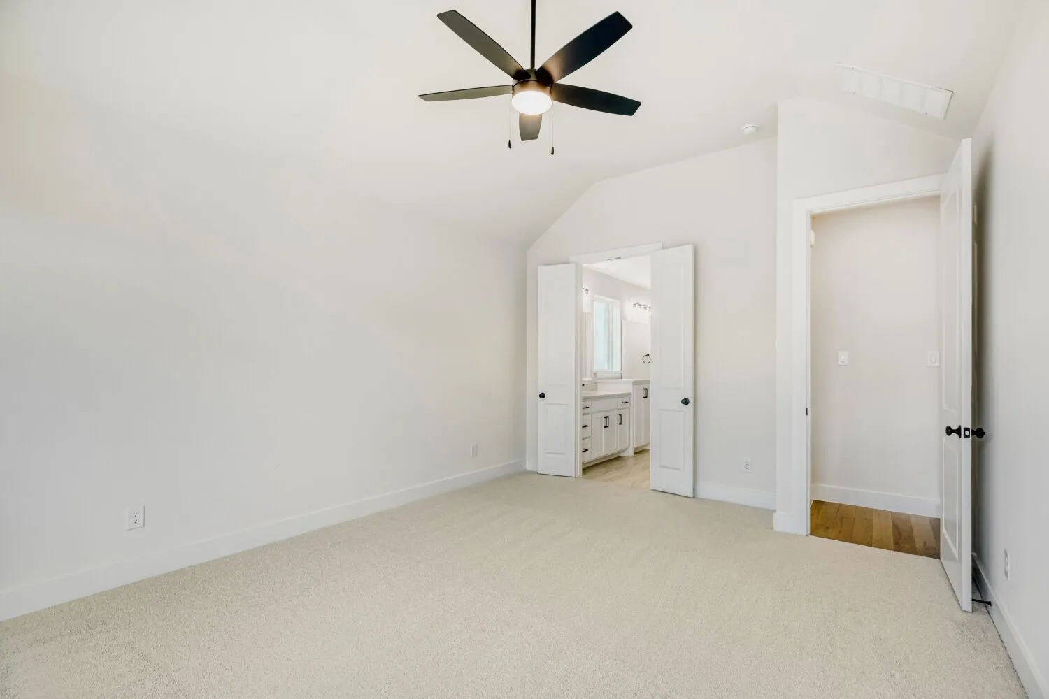 Carpeted room featuring a vaulted ceiling with a ceiling fan, white baseboards, and white walls