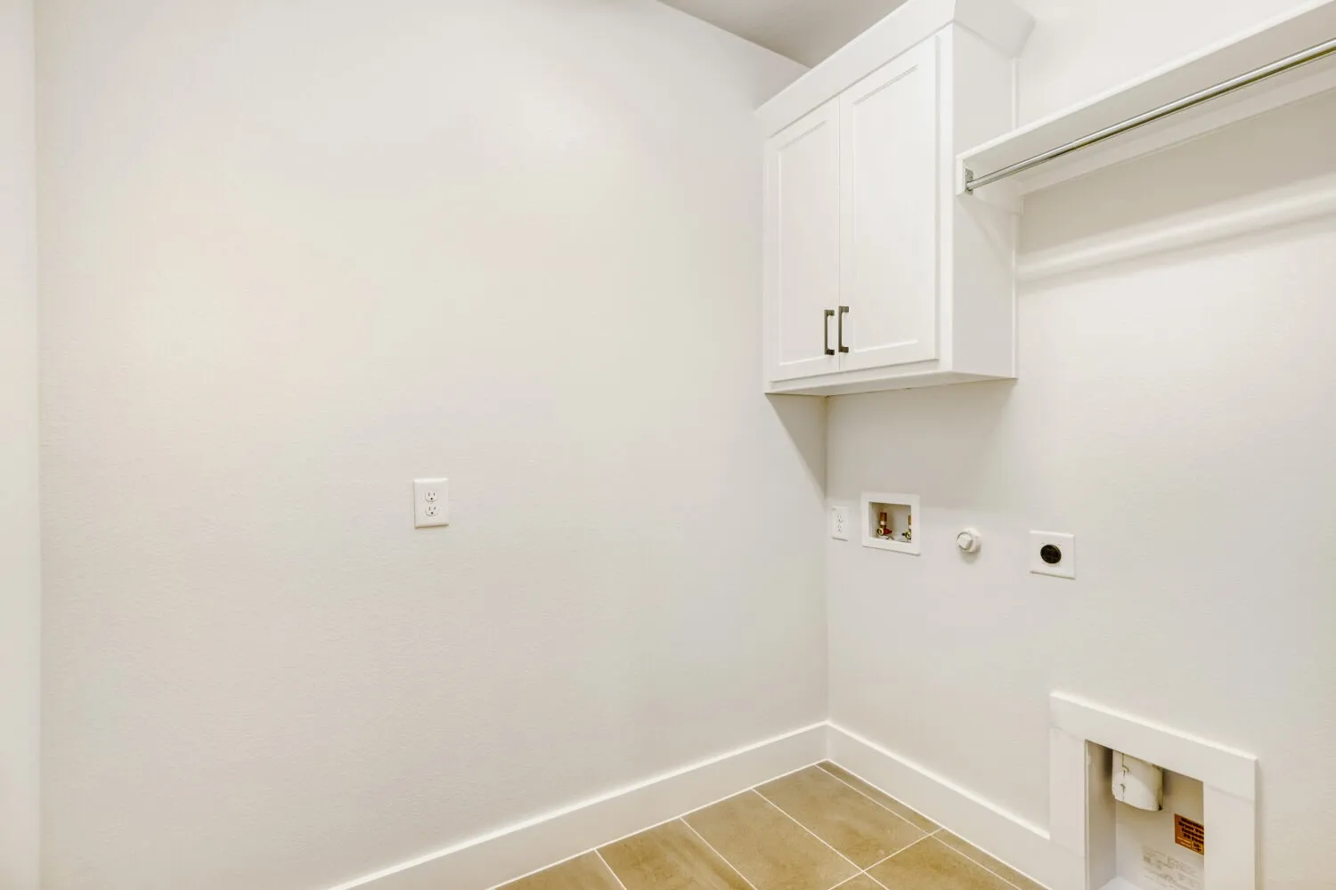 Laundry area featuring neutral-toned tile flooring, crisp white walls, built-in cabinetry with dark hardware, a hanging rod, and utility hookups
