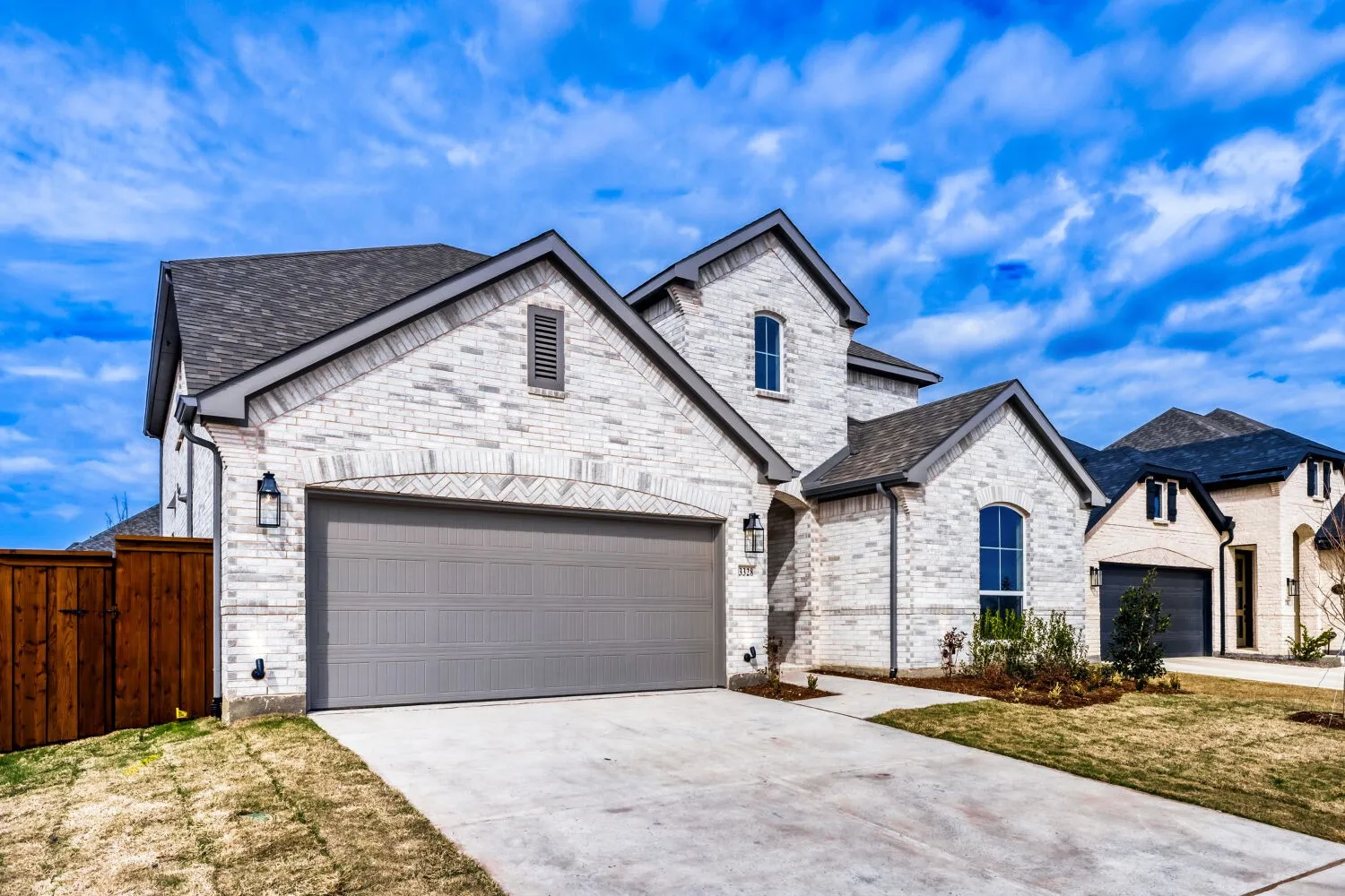 Contemporary residence featuring a light brick exterior with dark gray trim, an attached two-car garage with a matching dark gray door, and a concrete driveway