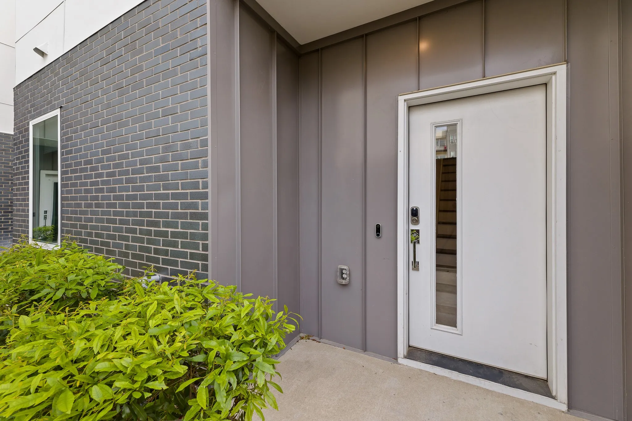 Property entrance with board and batten siding and brick siding