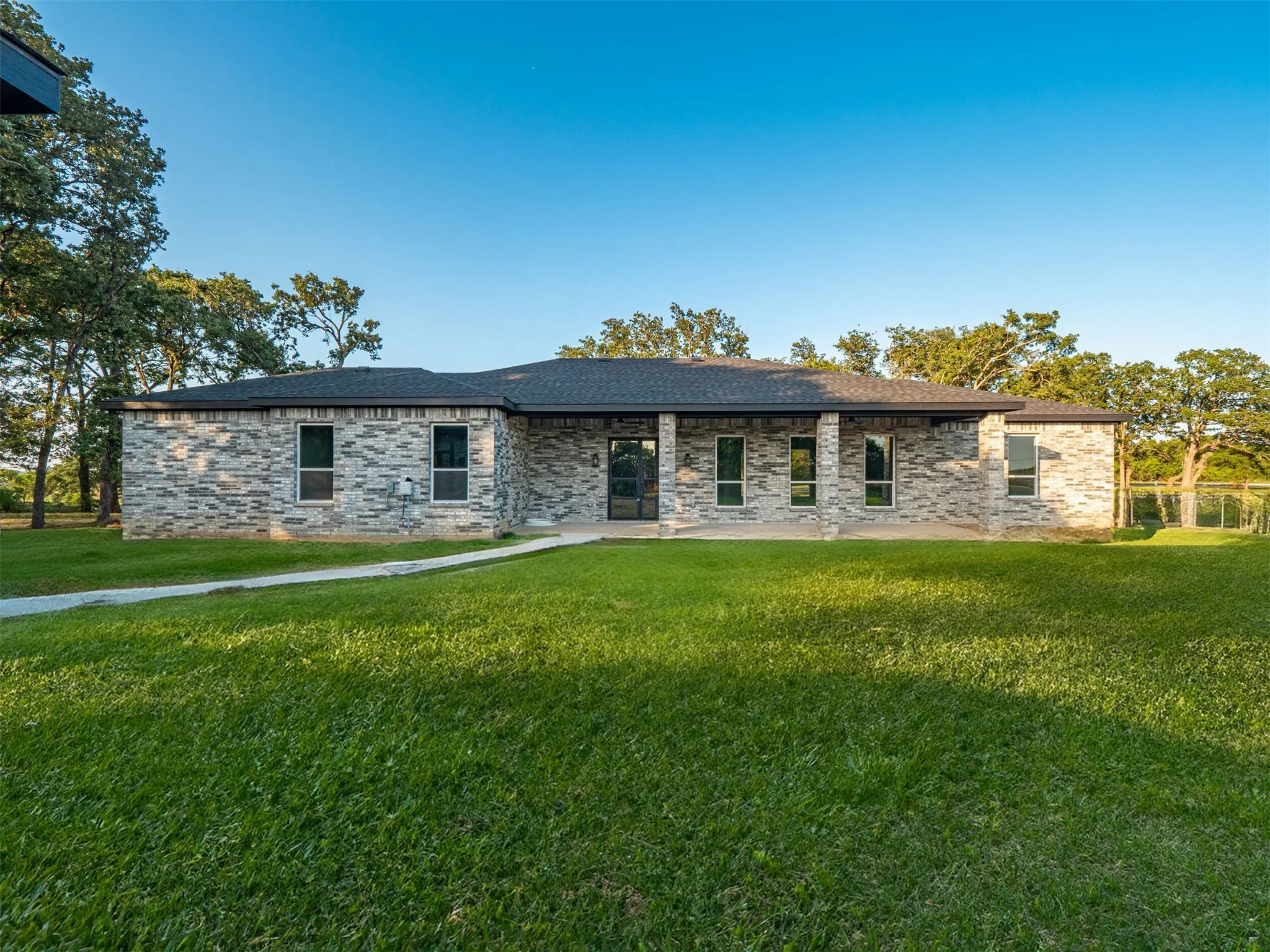 View of front of home featuring a front yard, brick siding, and a patio