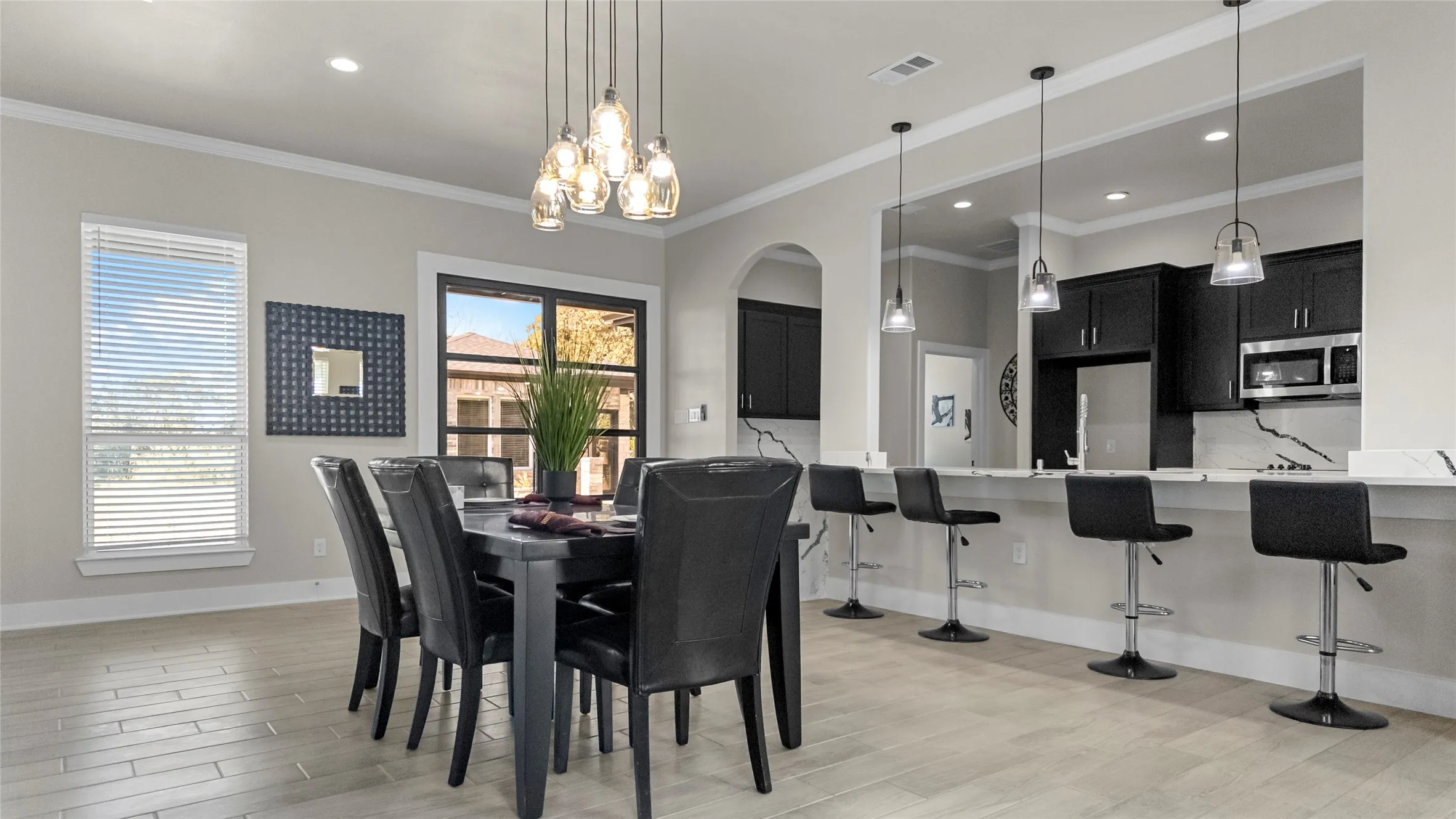 Dining room featuring crown molding, light wood-style floors, recessed lighting, arched walkways, and a chandelier