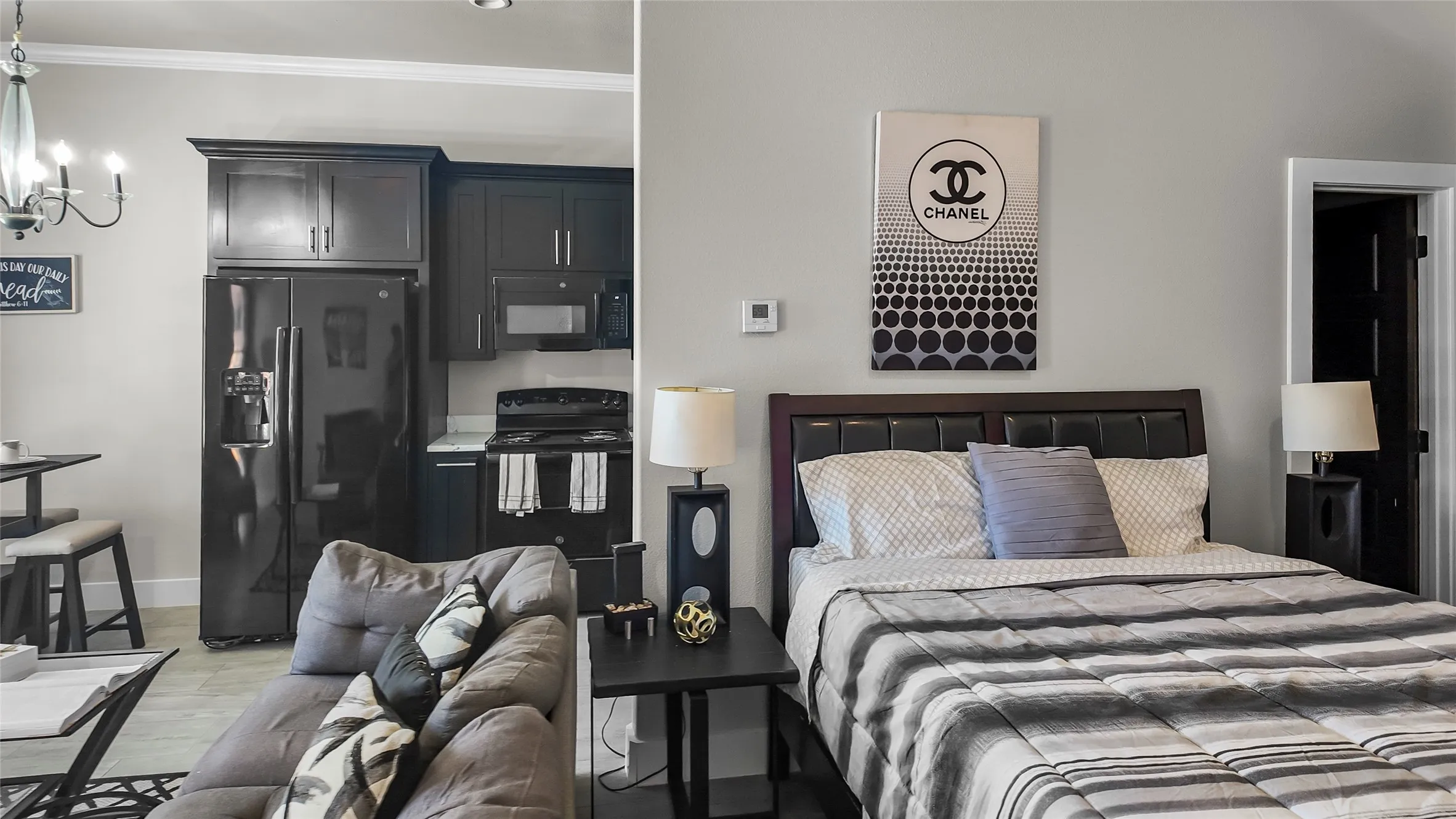 Bedroom with black refrigerator with ice dispenser, light wood-style flooring, crown molding, and a chandelier