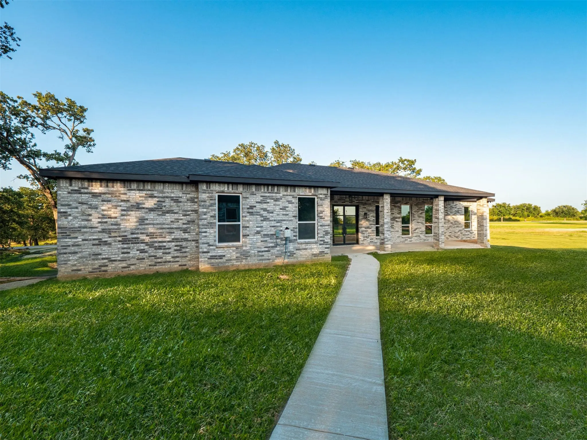 View of front of home featuring a front lawn, brick siding, and roof with shingles