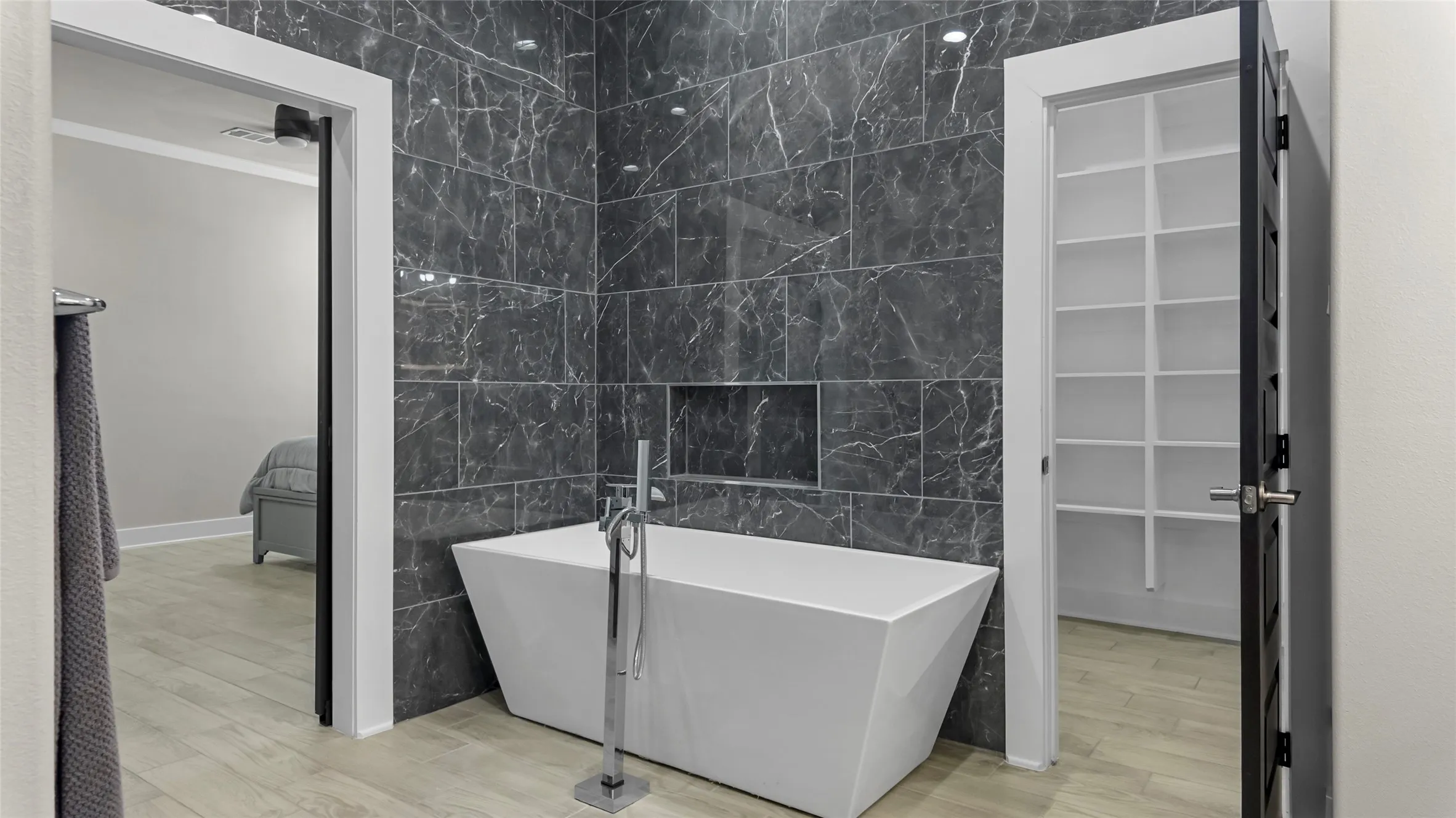 Full bathroom with tile walls, a soaking tub, light wood-style flooring, and ornamental molding