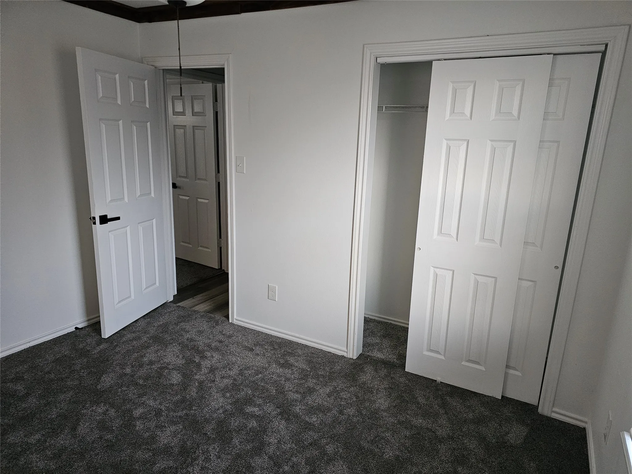 Unfurnished bedroom with dark carpet and a closet